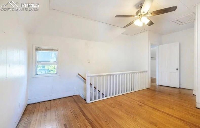 Empty room featuring hardwood / wood-style flooring, attic access, and ceiling fan