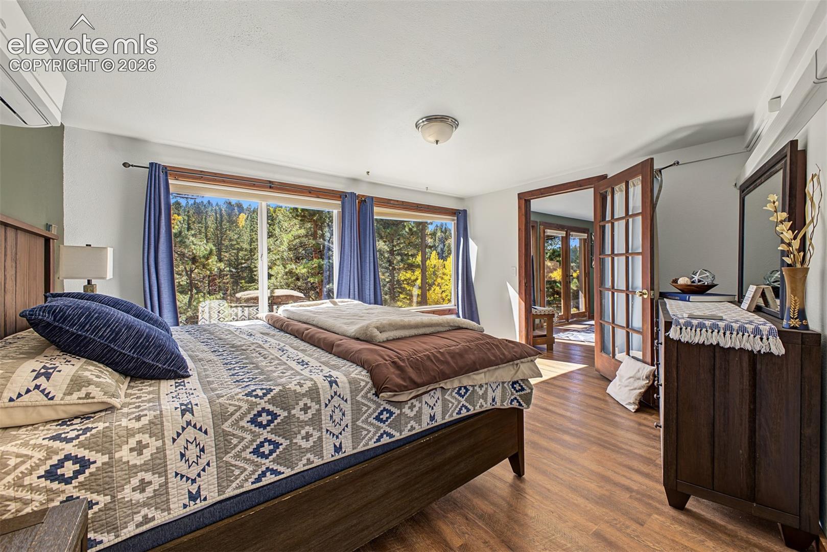 Expansive window wall, wood-finish flooring, white ceiling, ceiling-mounted light fixture, and interior French doors