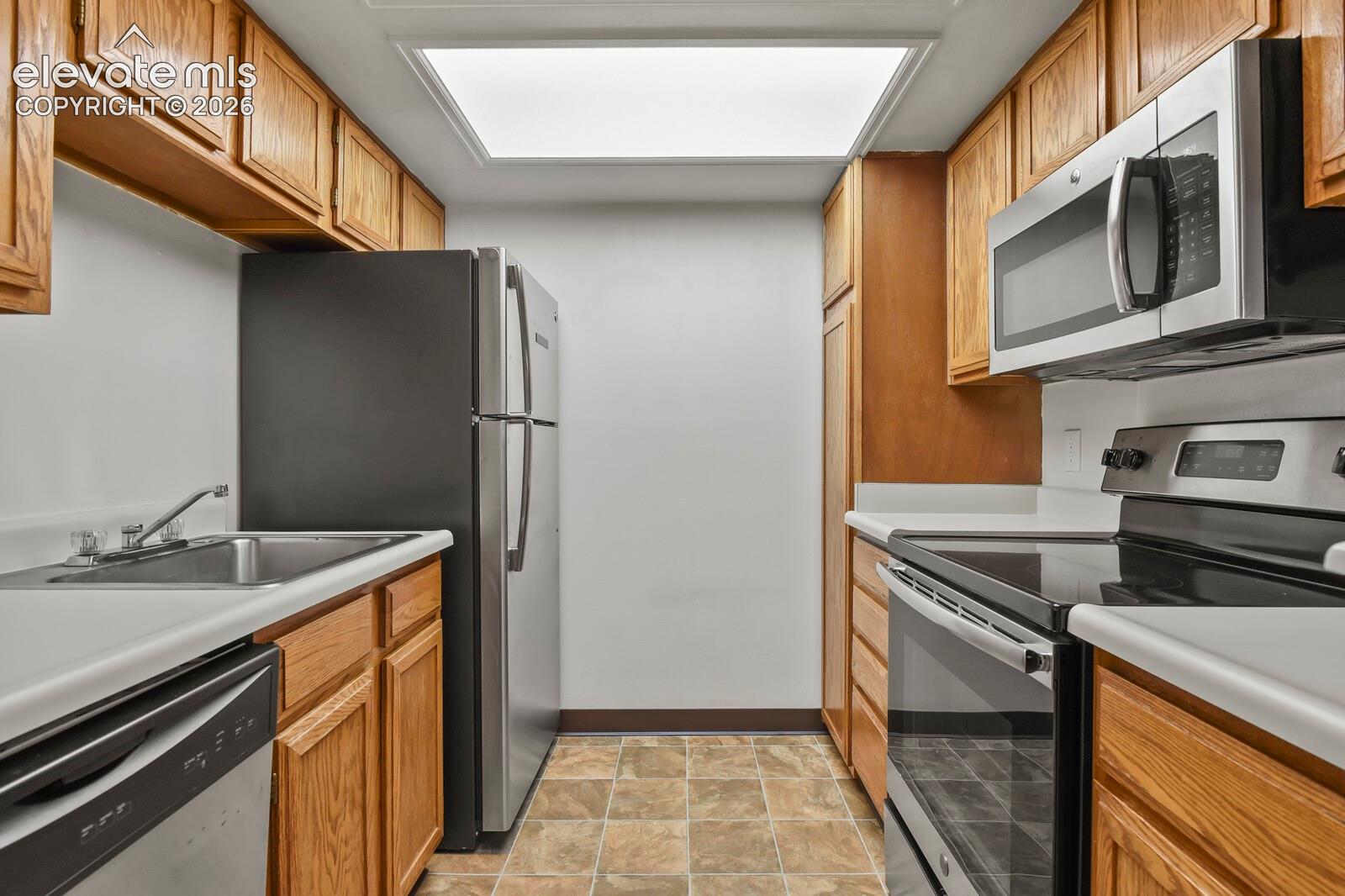 Kitchen featuring natural wood cabinetry, stainless steel appliances, recessed ceiling lighting
