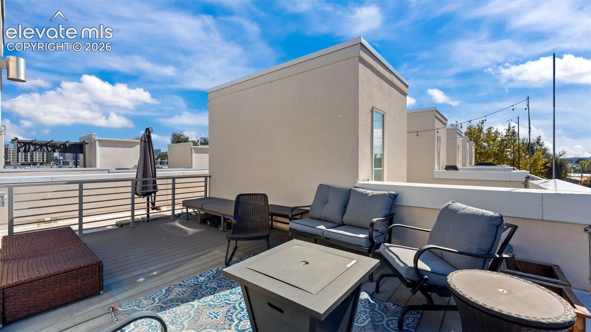 Rooftop terrace featuring composite decking, metal railings, and integrated string lighting
