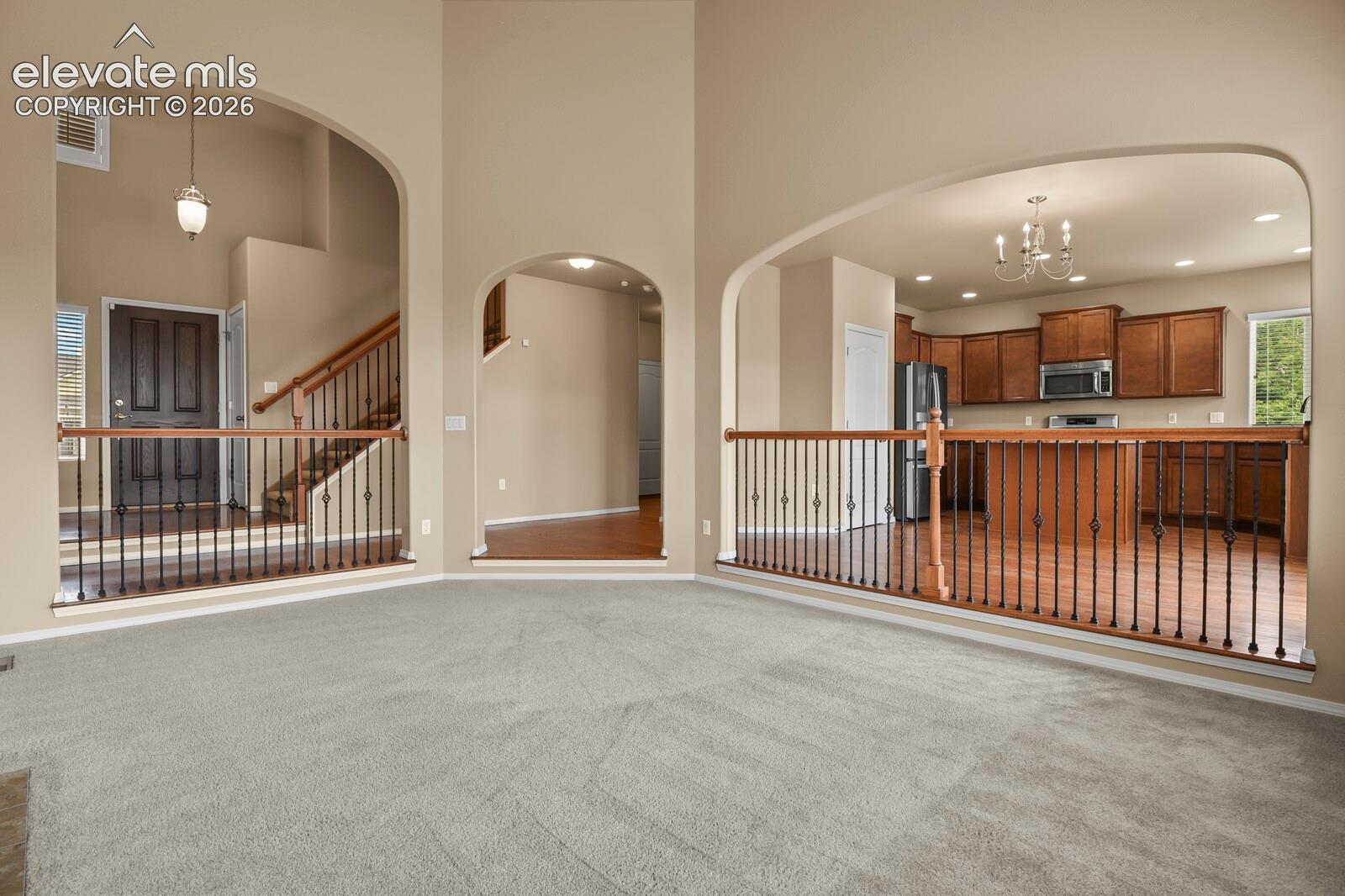 Arched doorways, open-concept design, wood-finish flooring, staircase with wrought iron balusters, and dark wood kitchen cabinetry