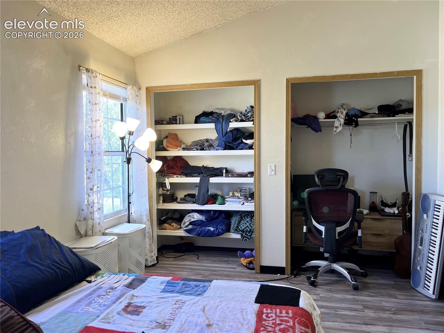 Vaulted ceiling, wood-finish flooring, two large recessed closet spaces with built-in shelving, and a double-pane window