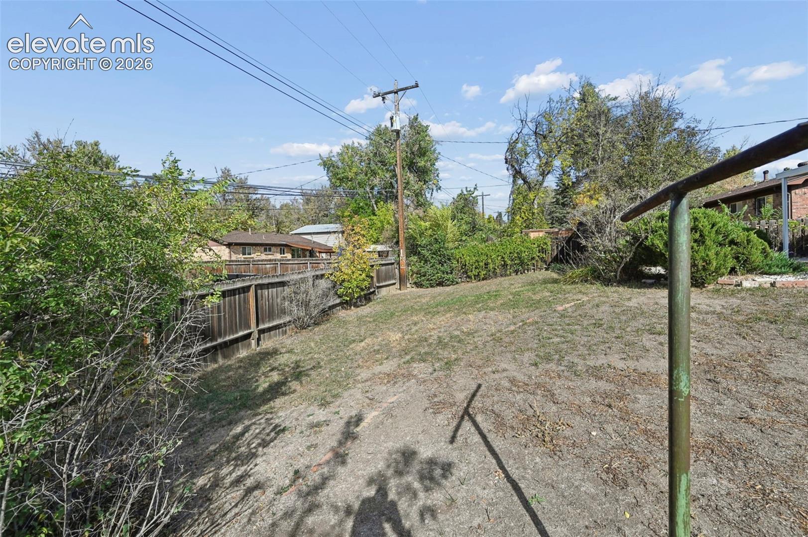 Expansive backyard featuring a wood privacy fence and mature landscaping