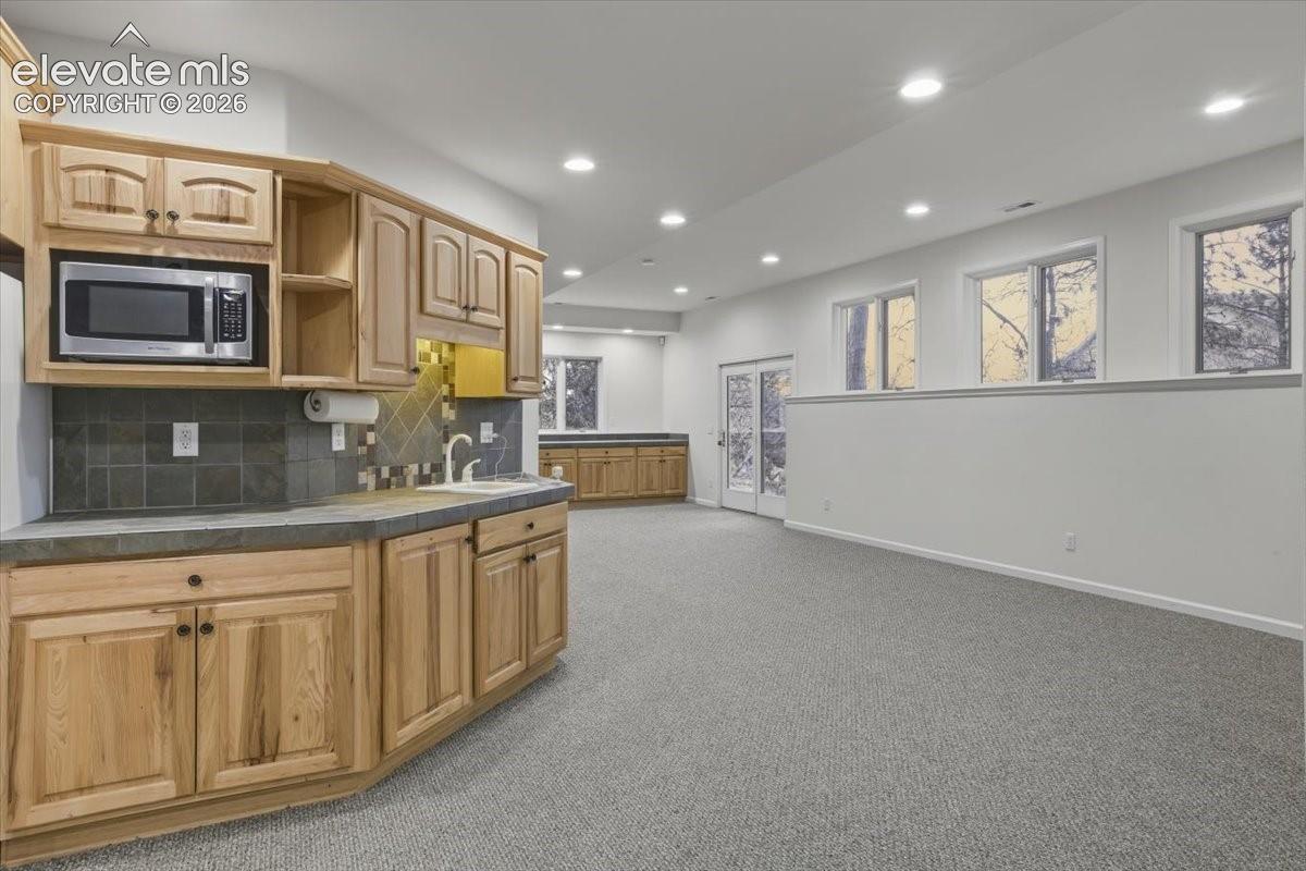 Recessed lighting, wood cabinetry, built-in microwave, tile backsplash.
