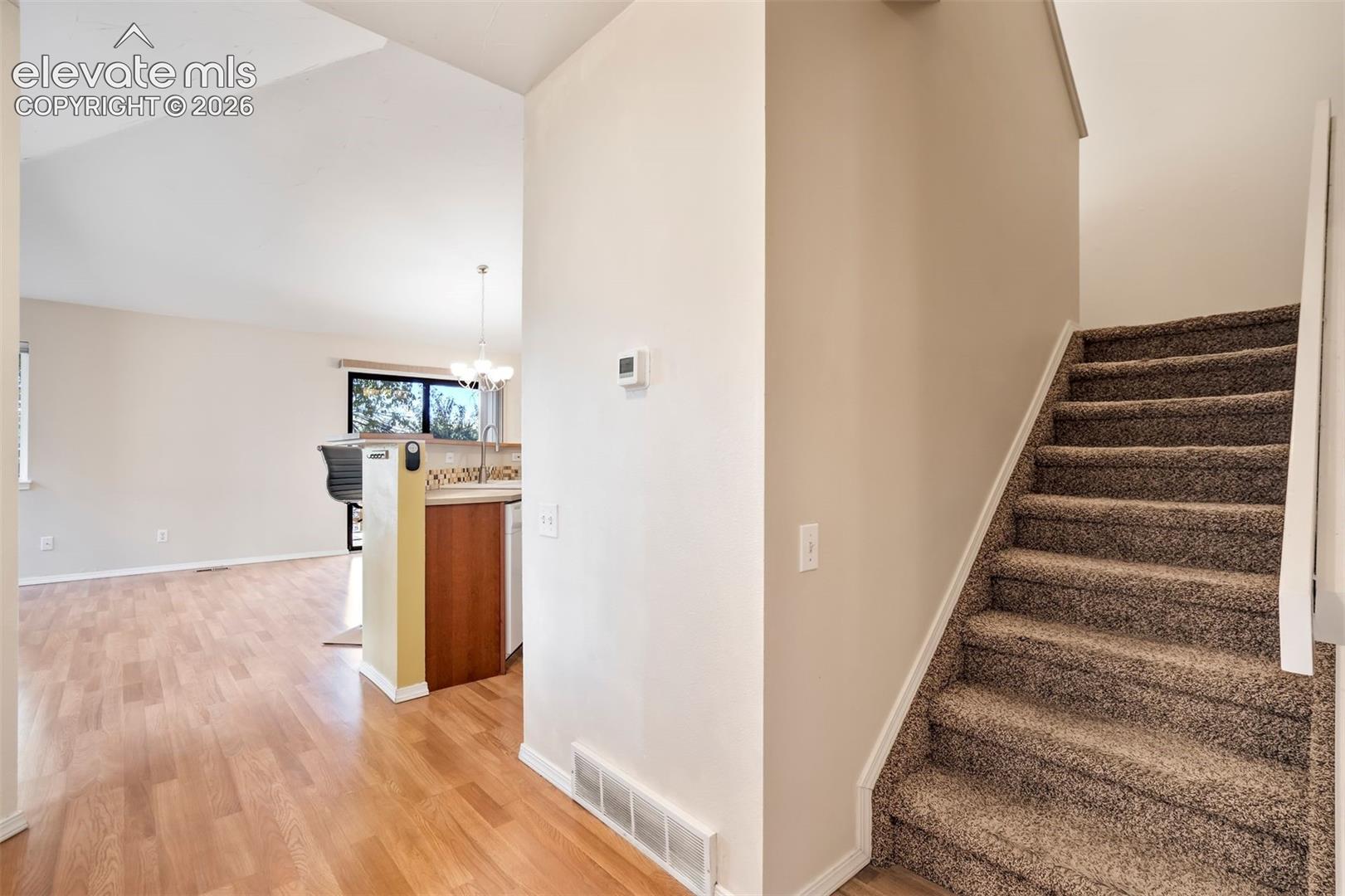 Interior staircase featuring neutral-toned carpeting and wood-finish flooring