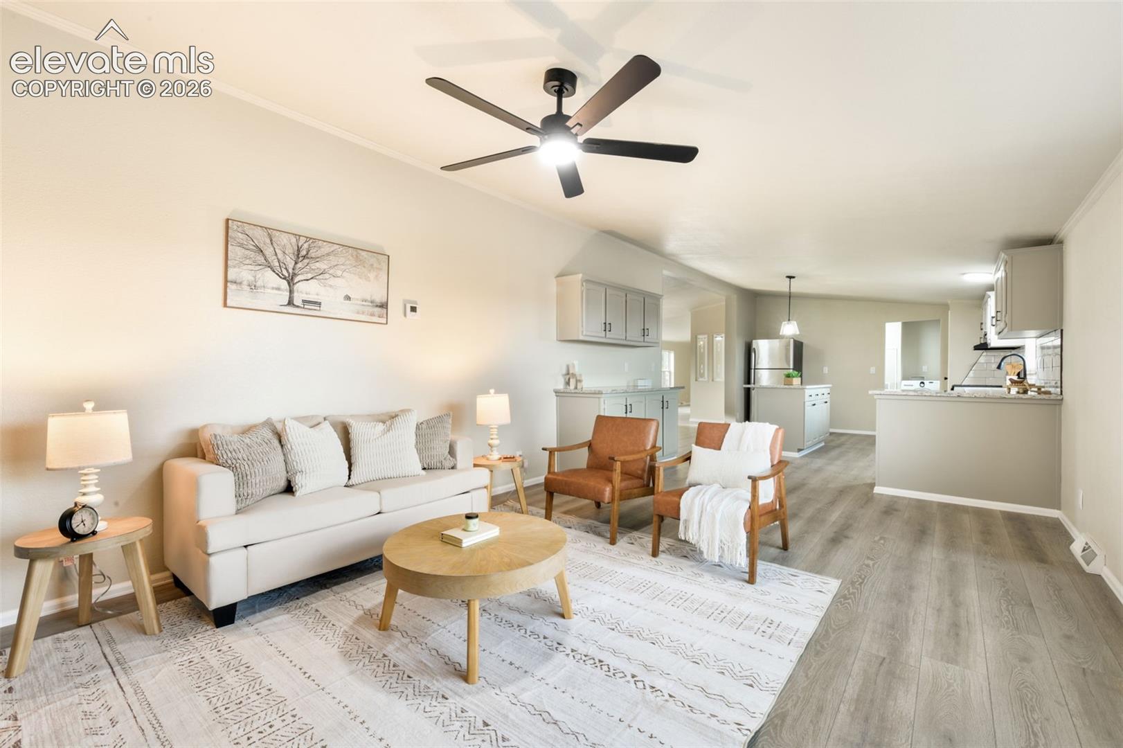 Open-concept living area with wood-finish flooring, a ceiling fan, and crown molding