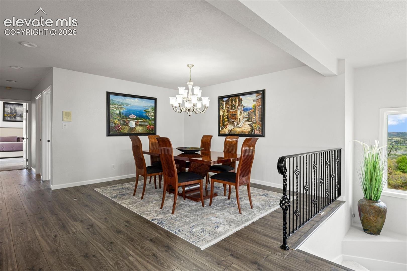 Formal dining room with crystal chandelier, open banister overlook to staircase, and adjacent access to the kitchen.