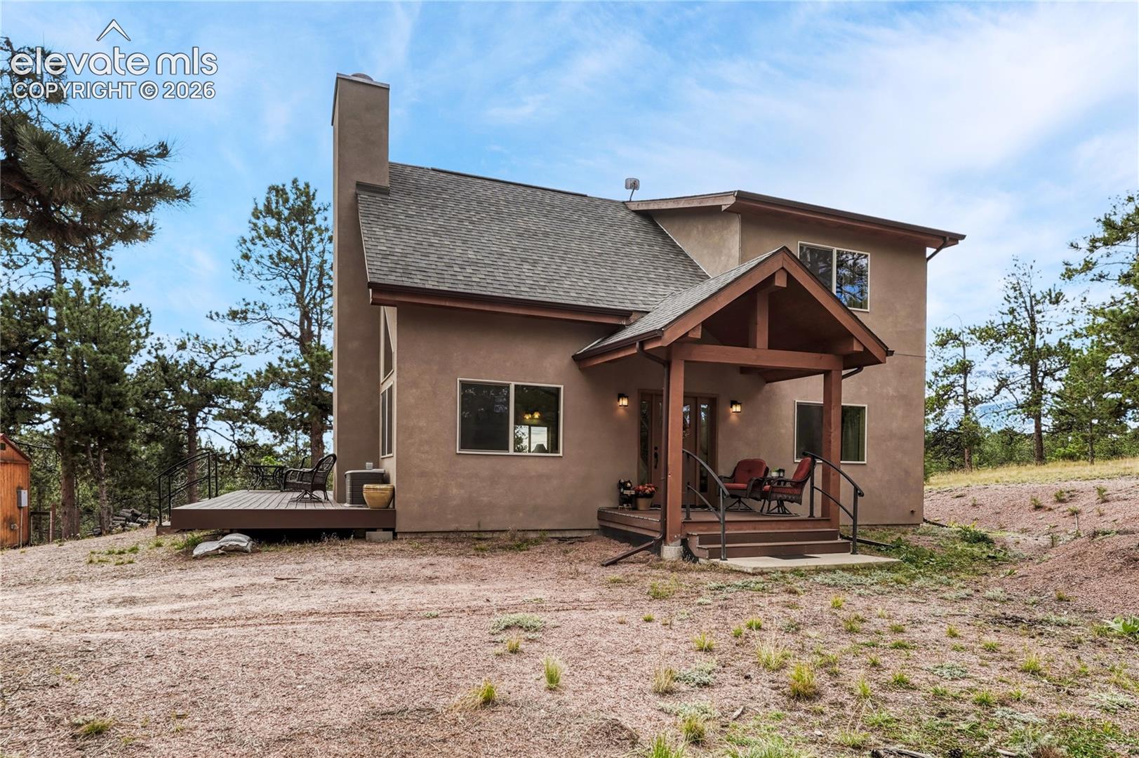 Stucco exterior featuring a prominent chimney, timber-frame covered porch