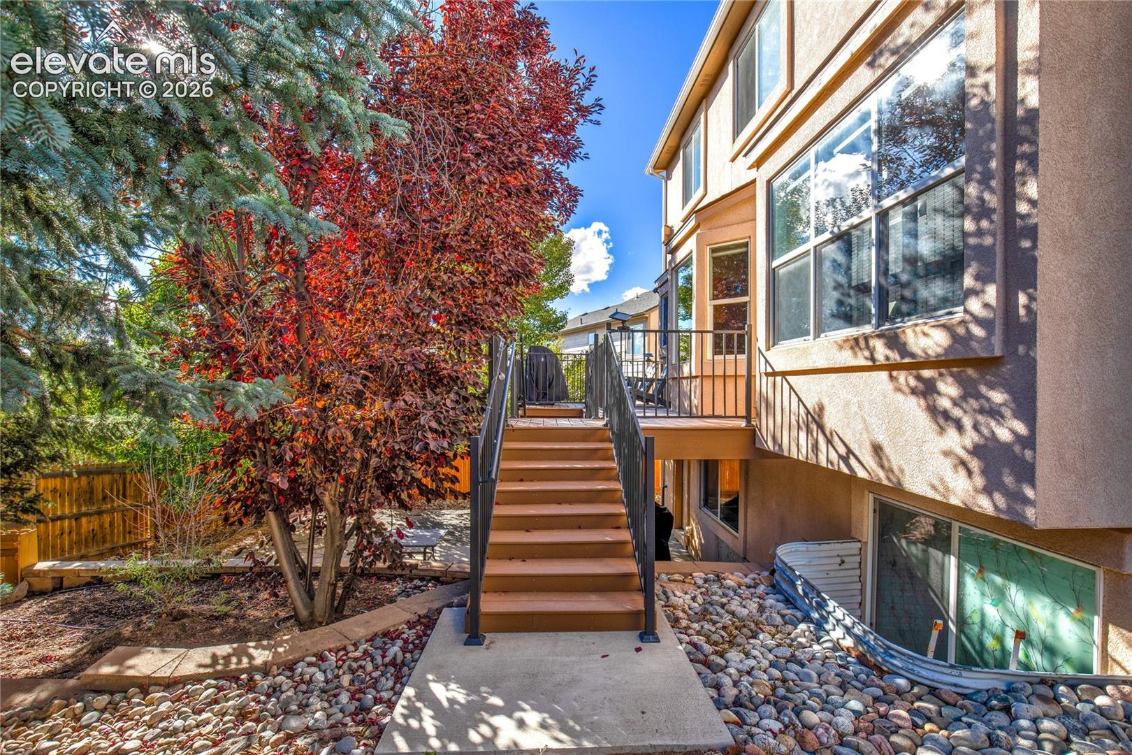 Exterior stairs connect the composite deck to the lower patio + fenced backyard, offering convenient access between the home's outdoor living spaces.