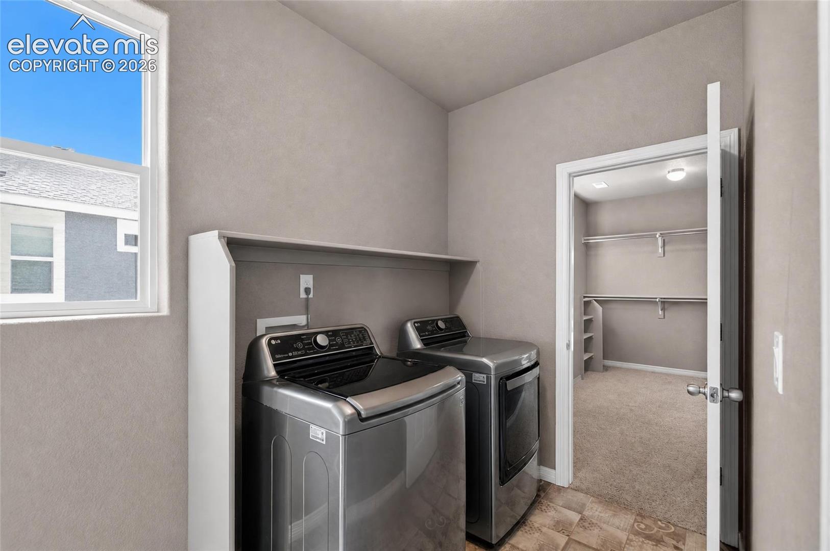 Laundry area featuring a window, built-in shelving, durable flooring, and convenient access to a separate walk-in closet with built-in shelving and hanging rods