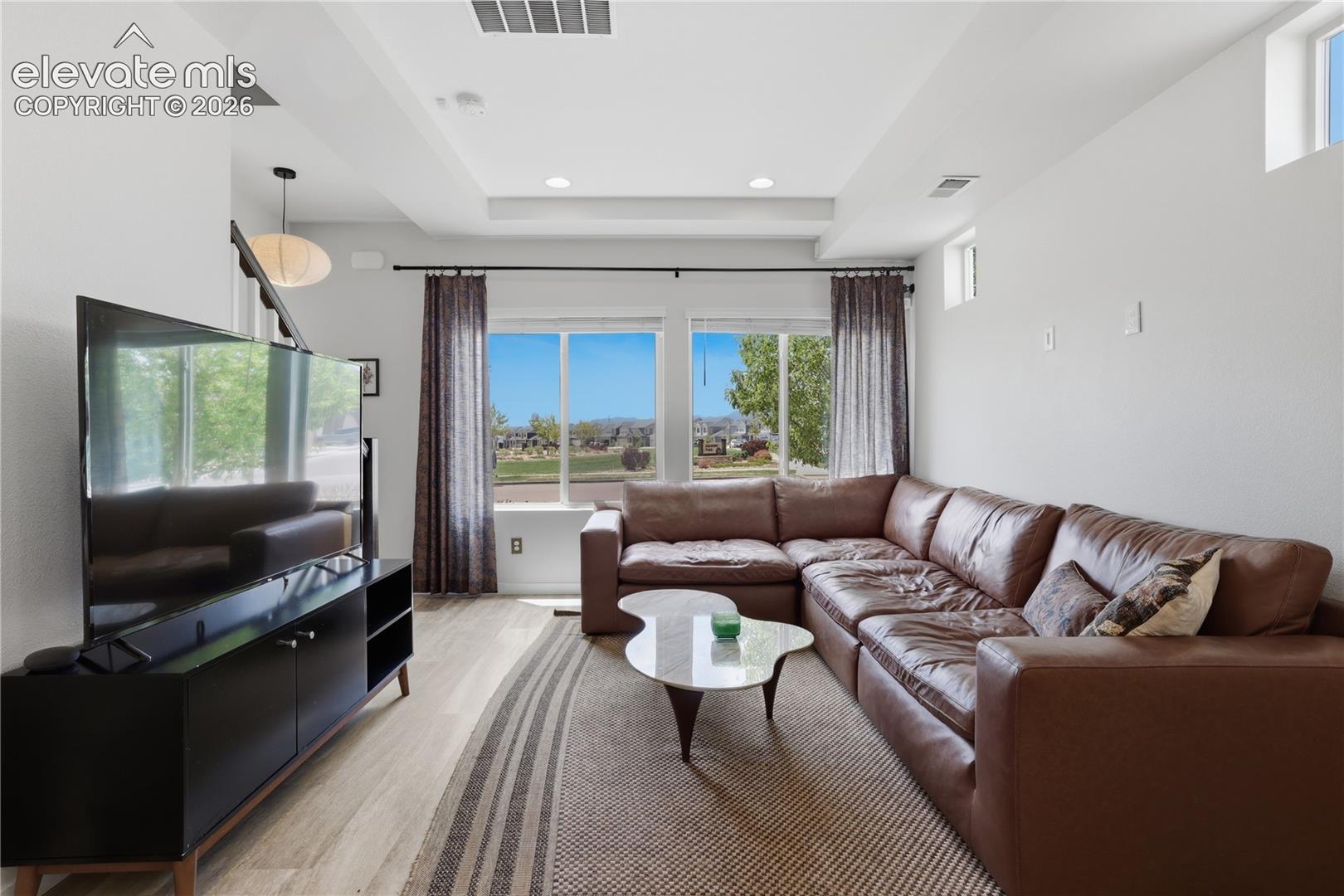 Living area with wood-finish flooring, recessed lighting, and a tray ceiling