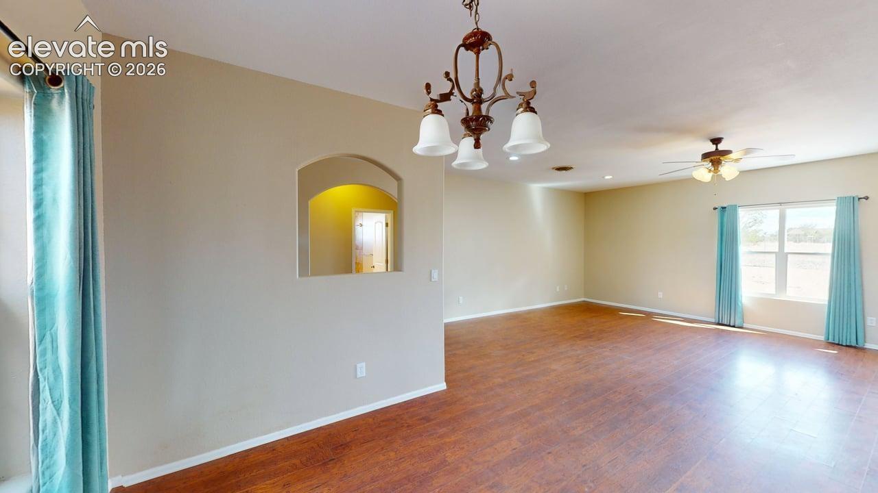 Expansive interior featuring wood-finish flooring, an arched wall niche, and an overhead chandelier