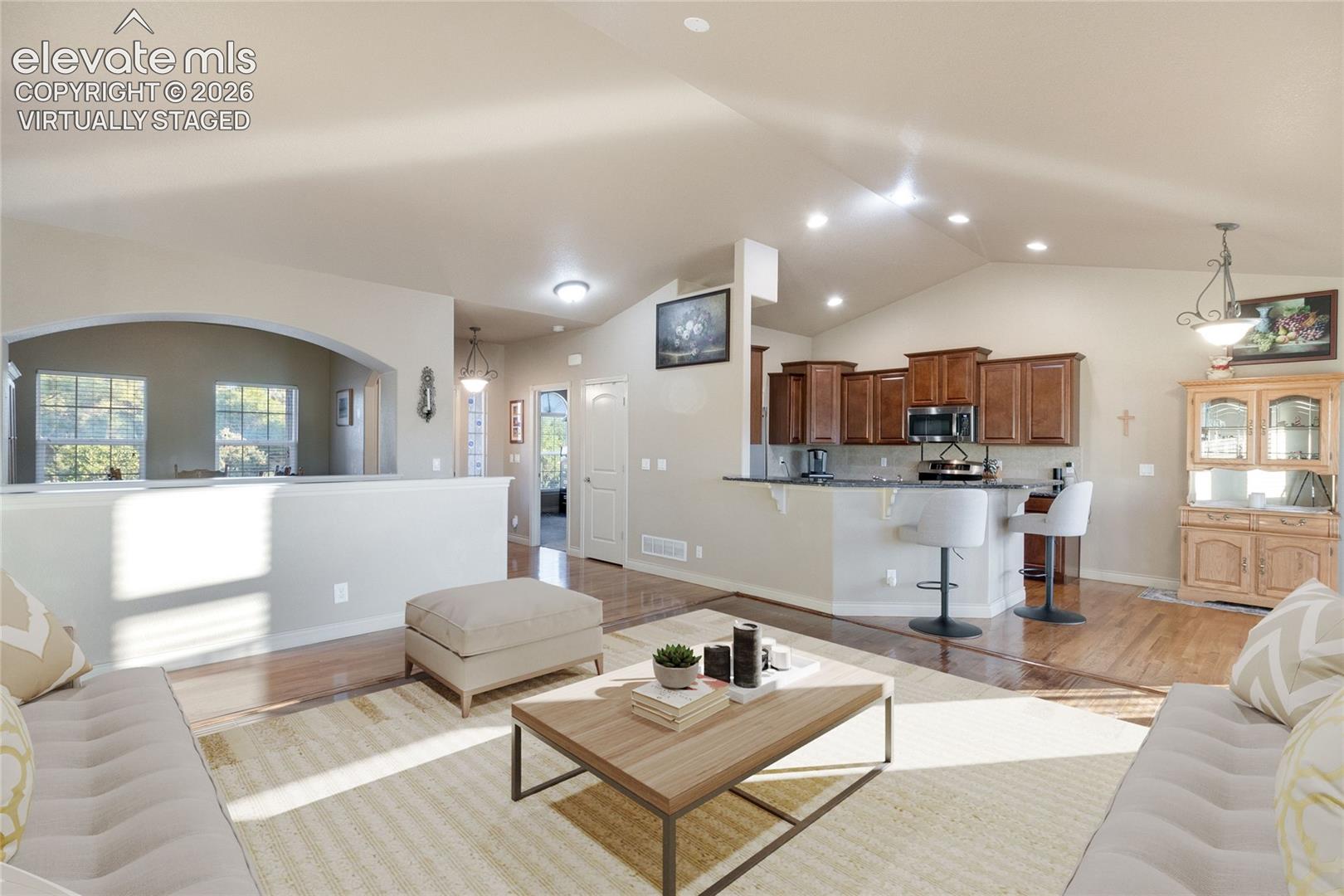 Virtually Staged; kitchen to the right, dining room to the left, foyer in middle background; wood floors, lots of light