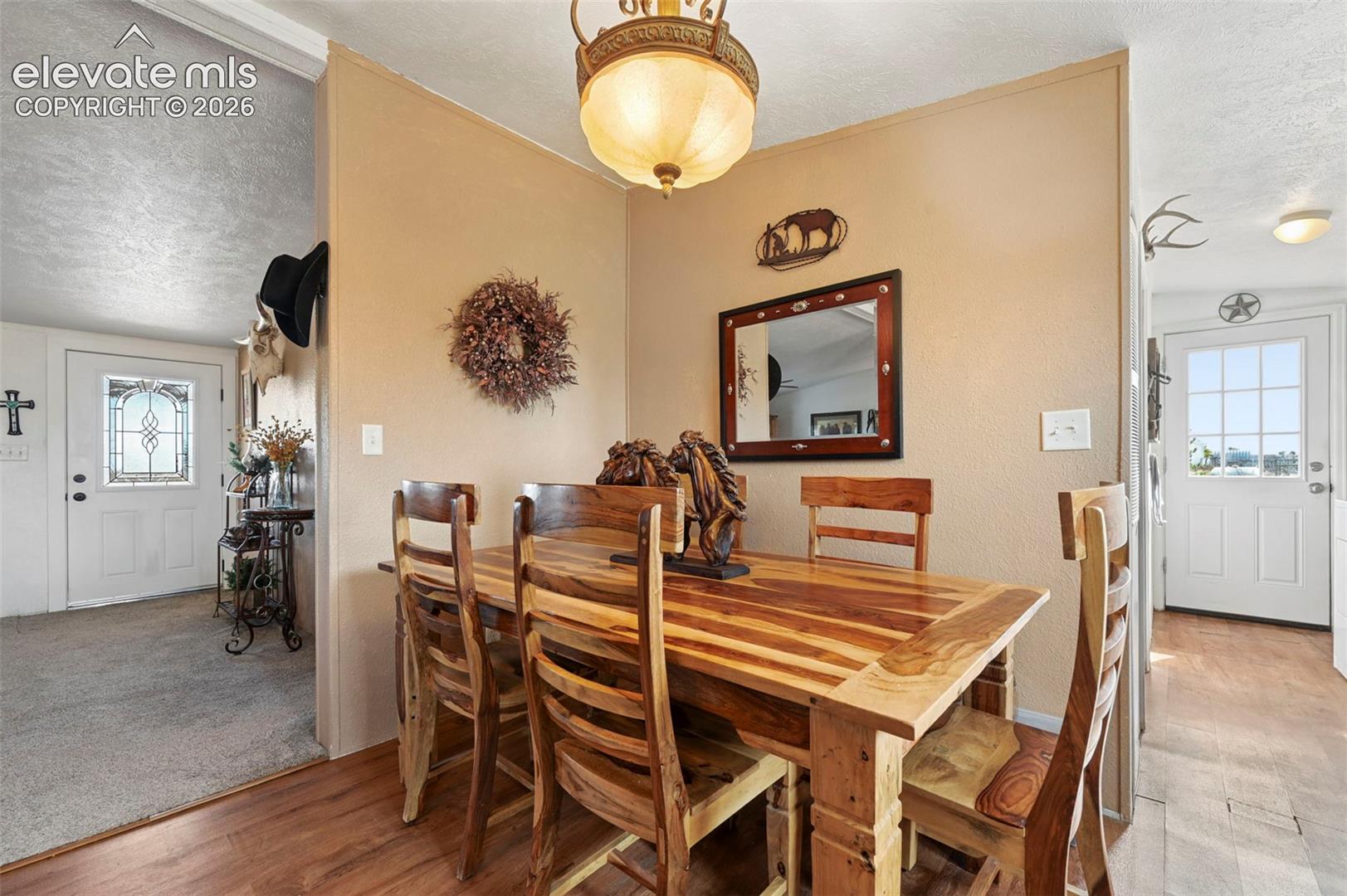 Dining area featuring wood-finish flooring, a decorative pendant light fixture, and two exterior doors with glass inserts