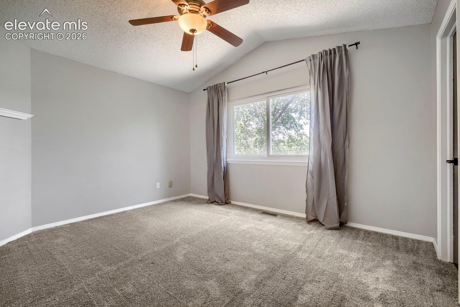 Carpeted room featuring a vaulted ceiling and a ceiling fan