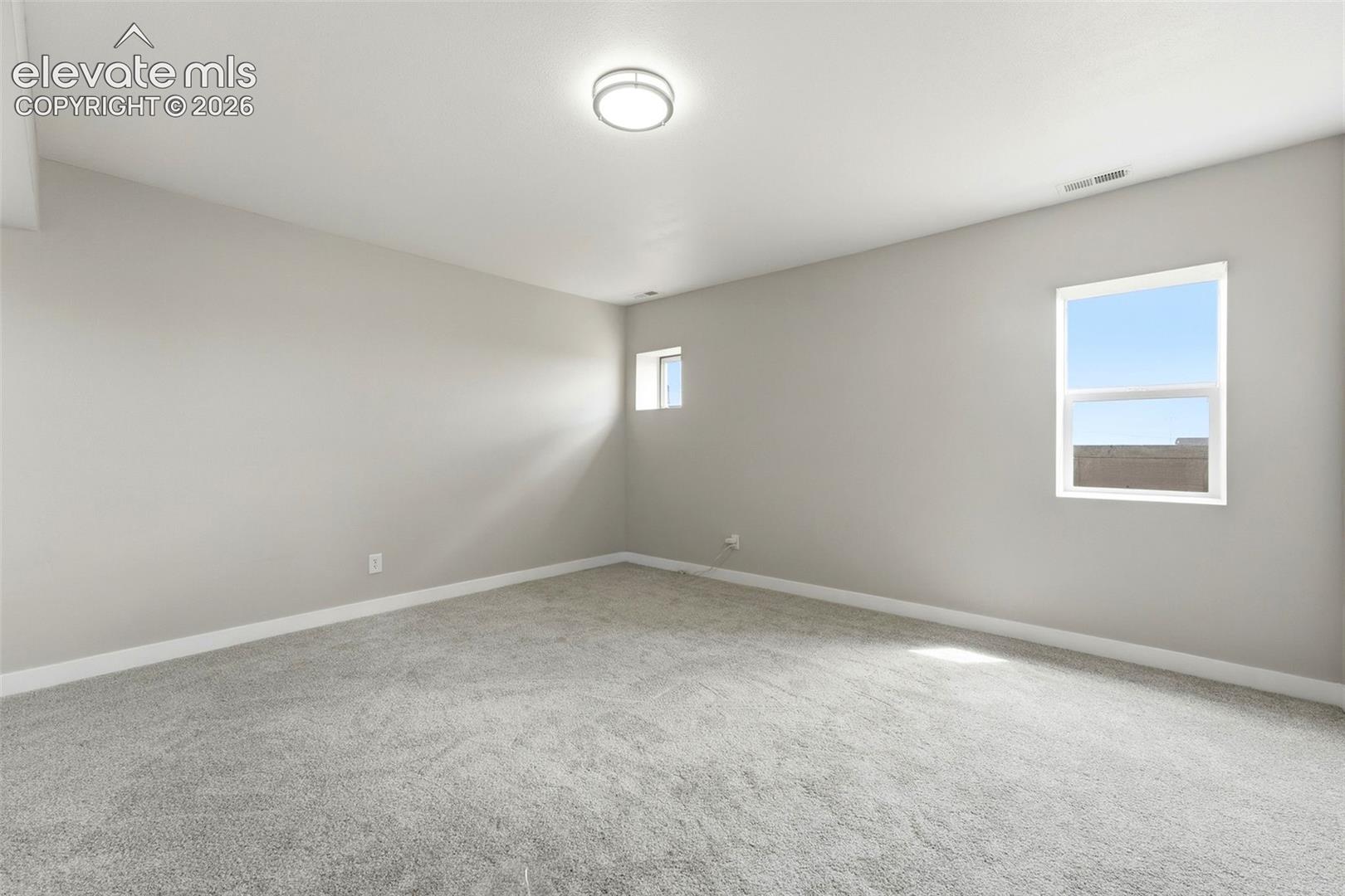 Plush gray carpeting, light neutral wall paint, white trim, recessed ceiling light, and multiple windows