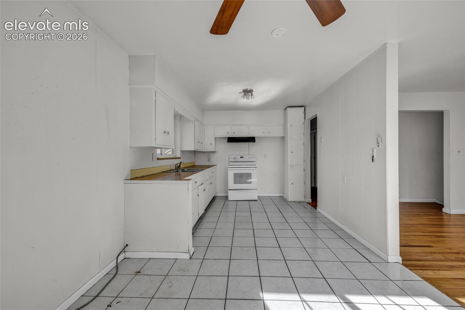 Kitchen with white cabinetry, tile flooring, and a ceiling fan