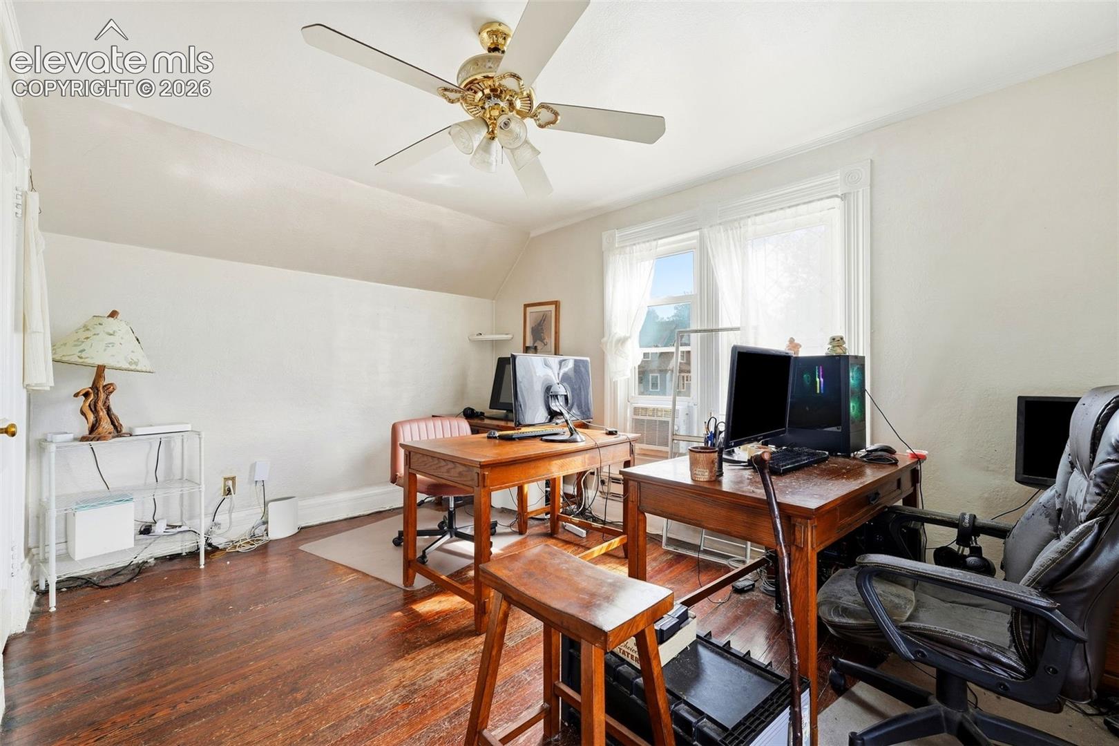 Room with wood-finish flooring, a ceiling fan, and a window with white trim