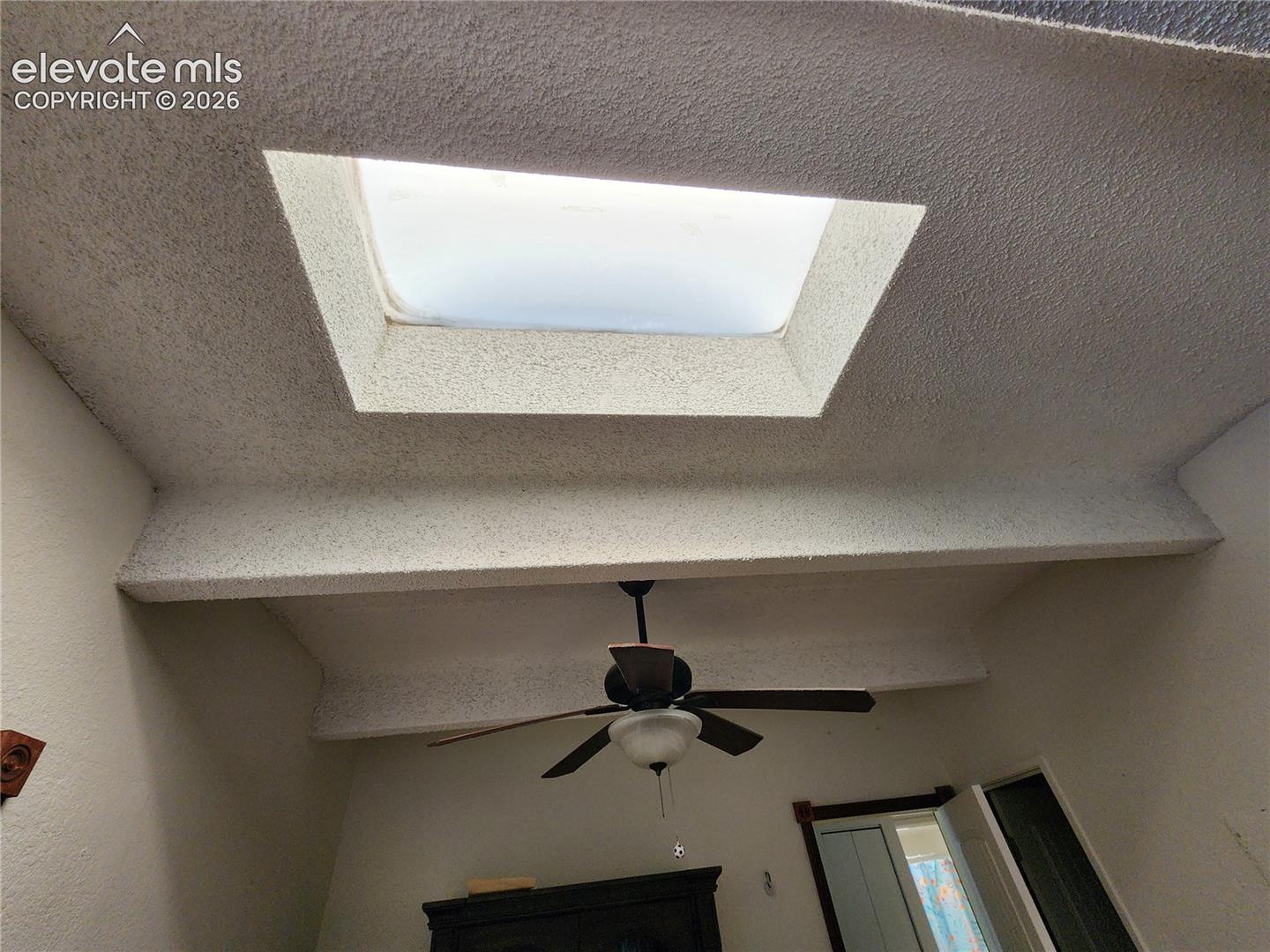 Vaulted ceiling featuring a recessed skylight and a central ceiling fan with integrated lighting