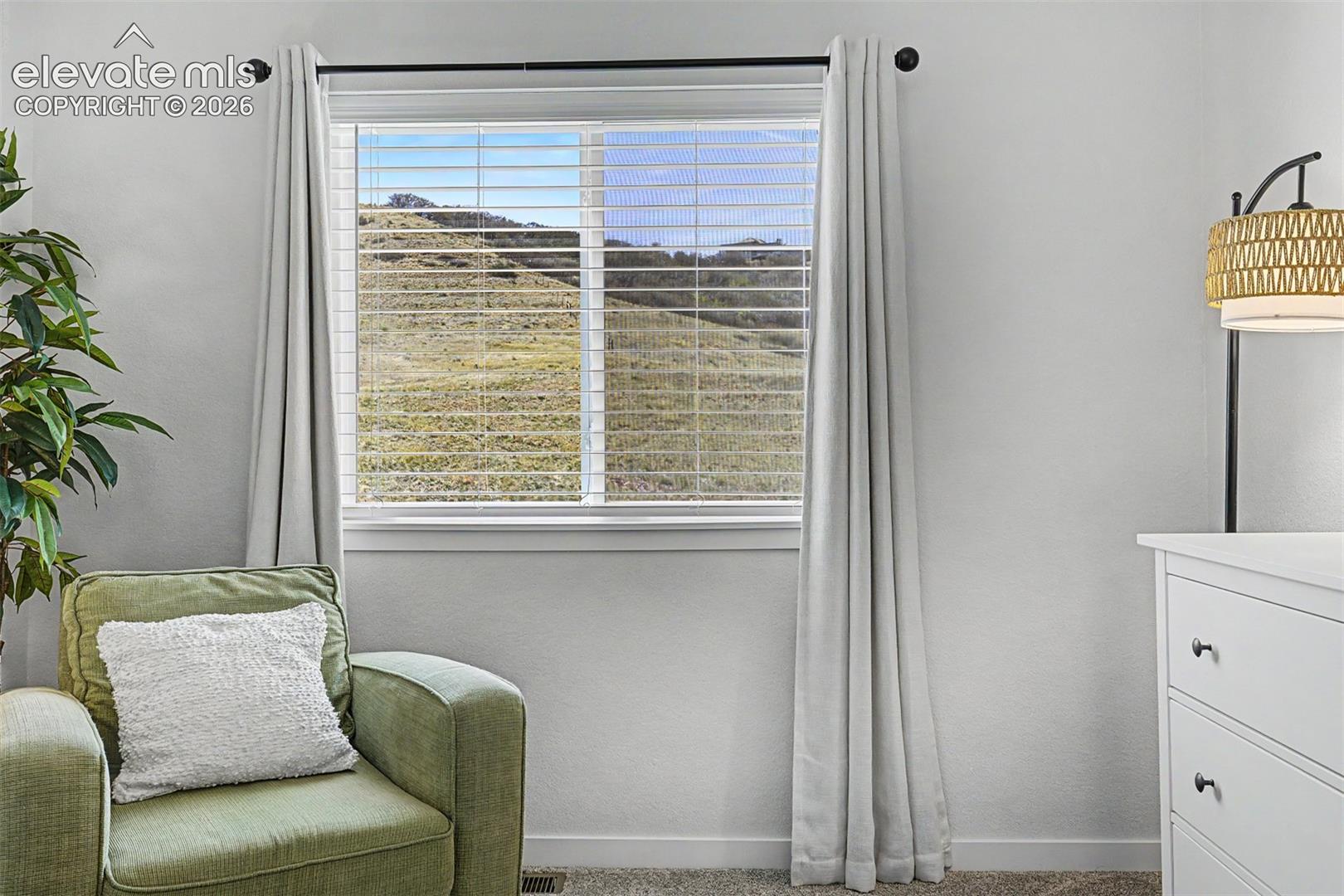 Rolling golden hills stretch toward the horizon beneath a vivid Colorado sky — a serene, ever-changing landscape that makes even this bedroom feel quietly connected to something much larger.