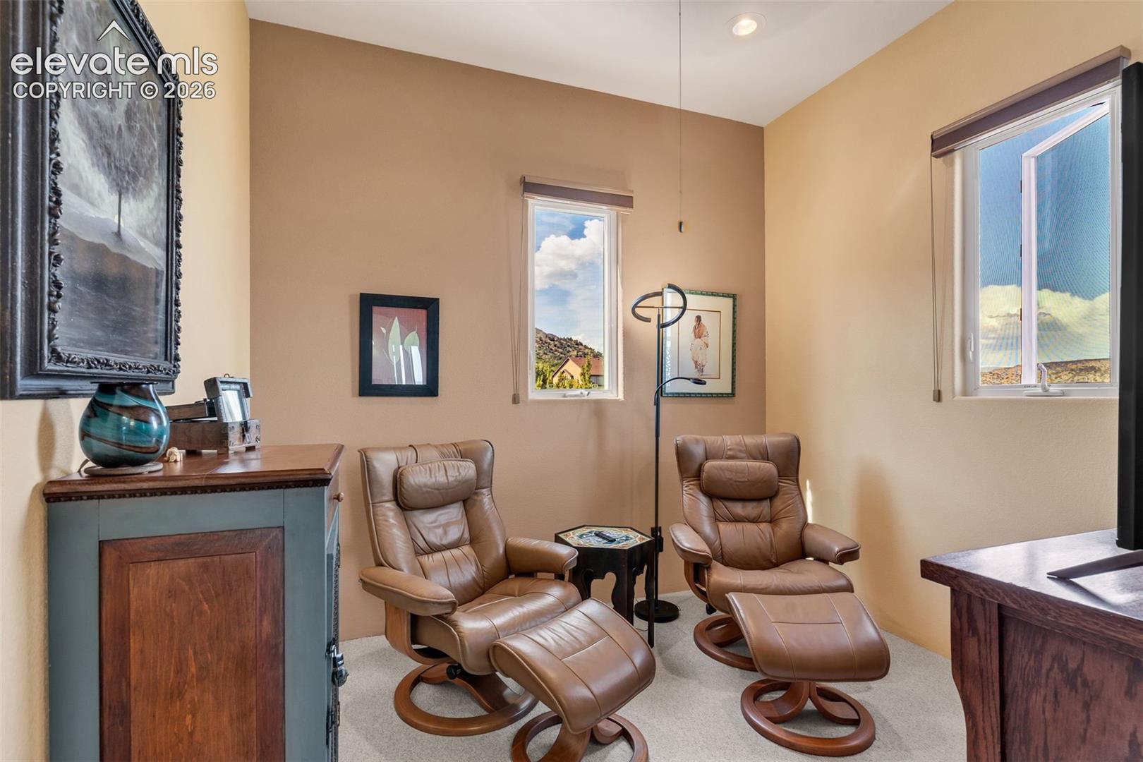Neutral-toned interior space featuring two vertical windows, recessed lighting, and wall-to-wall carpeting