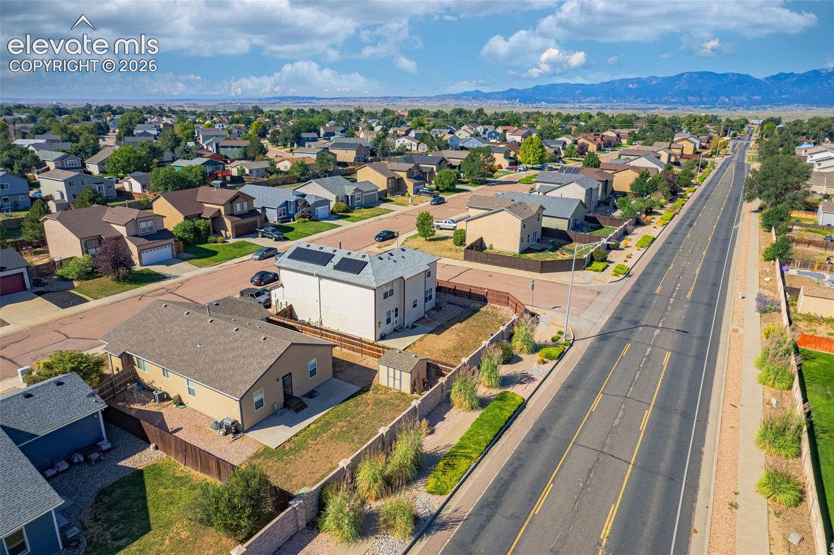 Residential neighborhood with paved streets, mature trees, and distant mountain backdrop
