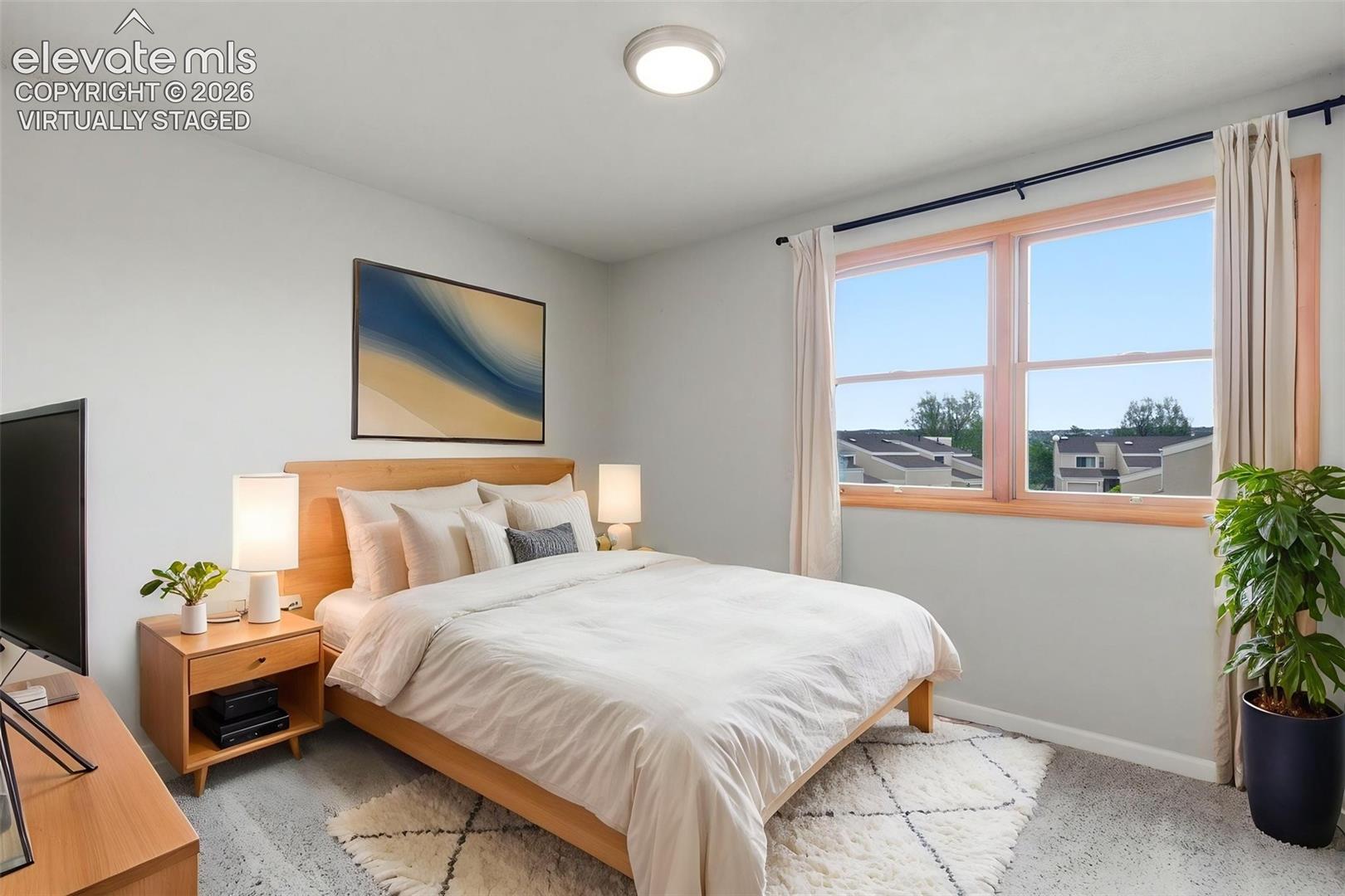 Virtually staged -
Light-filled room featuring a broad window, light-toned walls, and soft carpet flooring