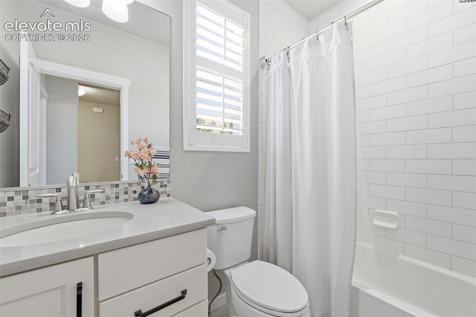 White shaker-style vanity with a light-toned stone countertop, undermount sink, and brushed nickel faucet.