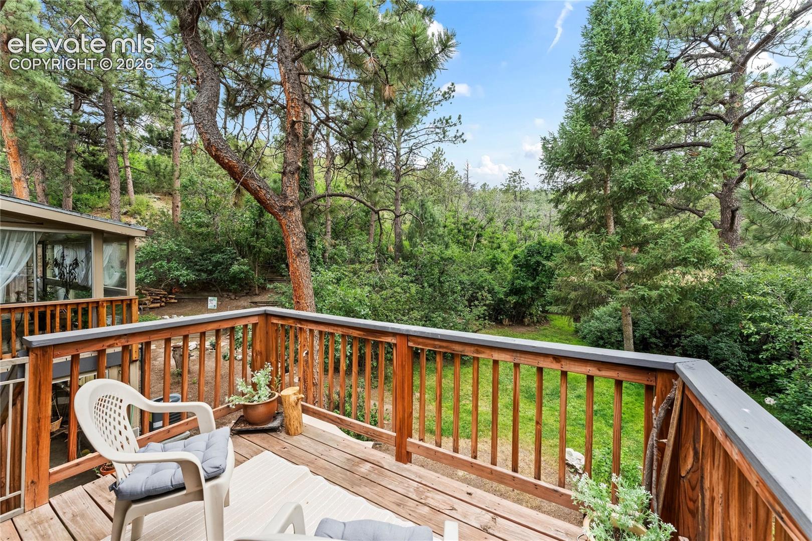 Wood-finish deck featuring a slatted railing and verdant surroundings