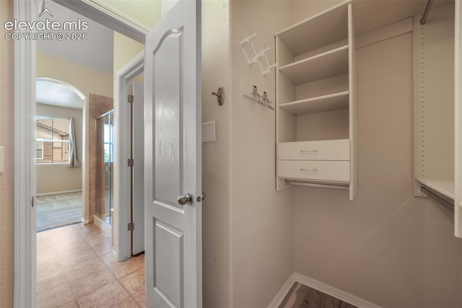 Walk-in closet with built-in shelving, drawers, and hanging rods