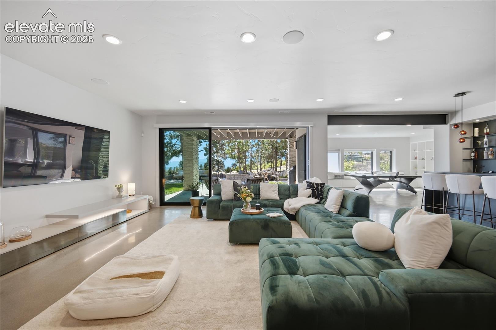 Recessed lighting, large format tile flooring, sliding glass doors, and a full-service bar