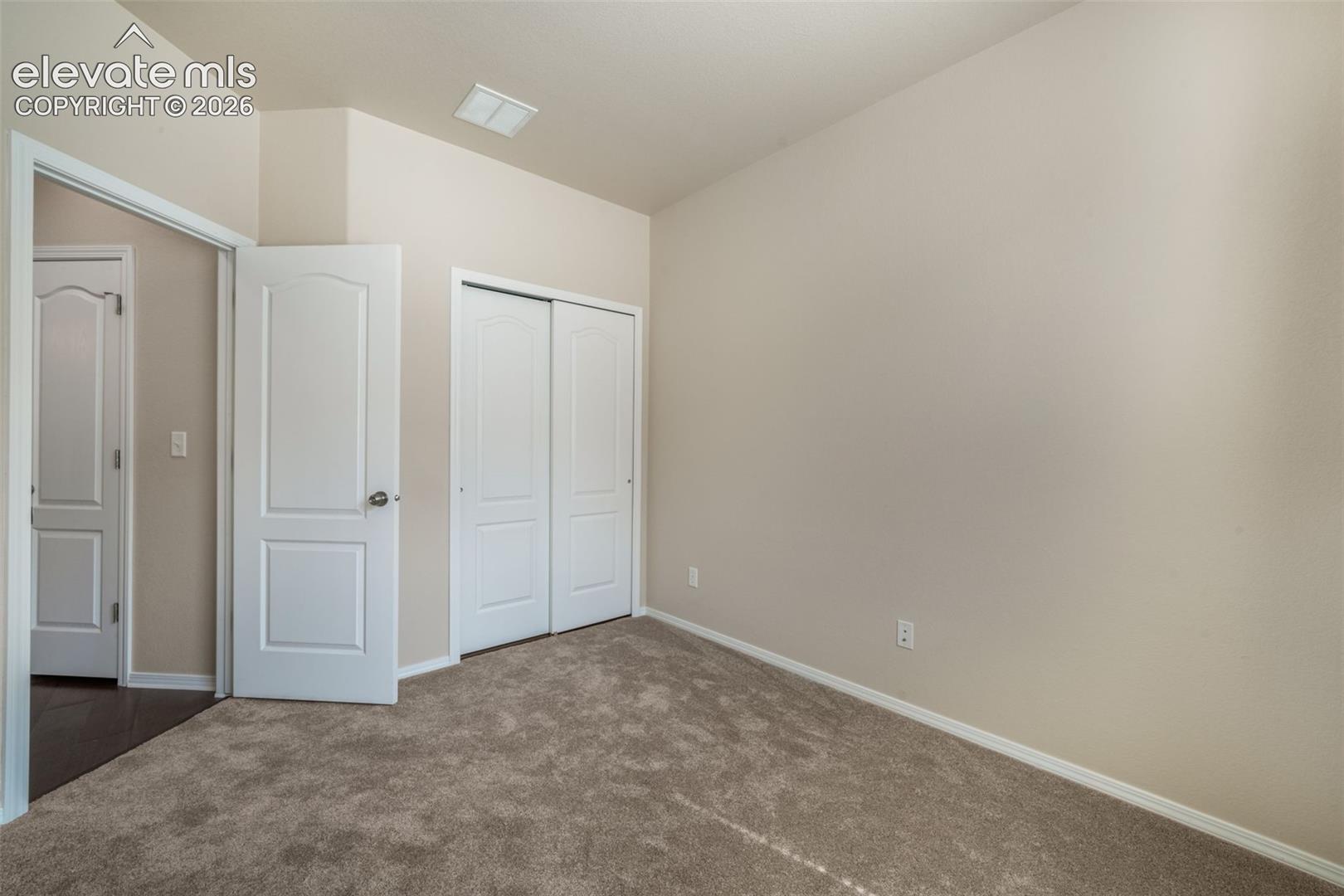 Carpeted flooring, neutral wall tones, white trim, white paneled doors, and a built-in closet with sliding doors