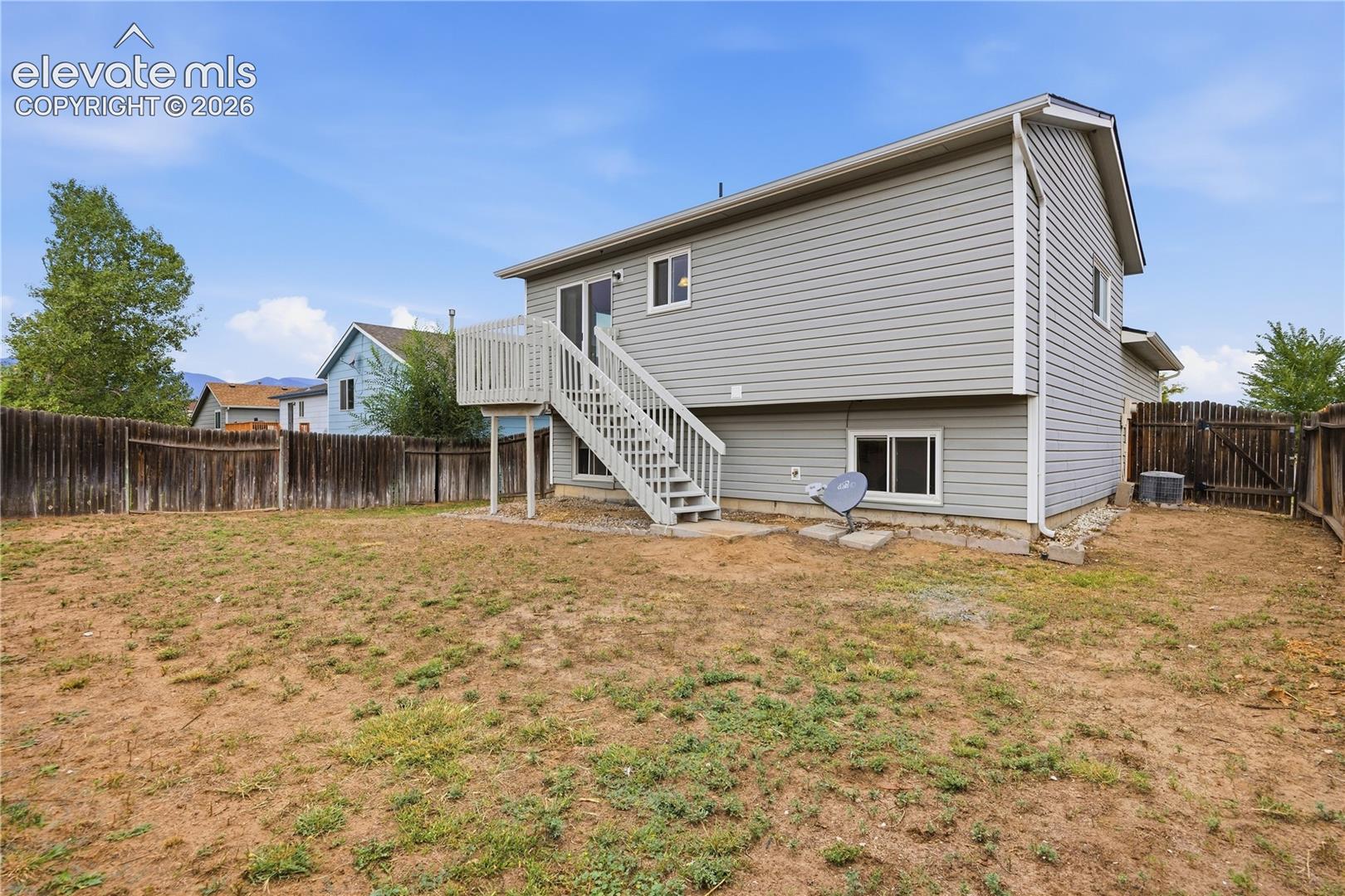 Exterior featuring horizontal lap siding, elevated wooden deck with stairs, and fully fenced backyard