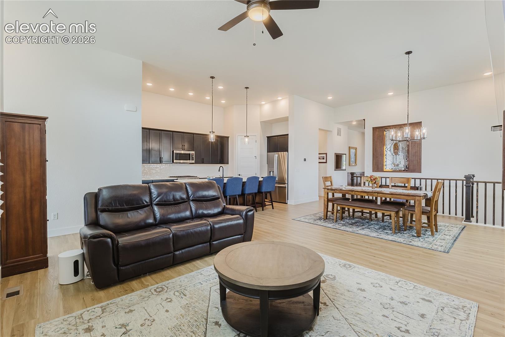 Open-concept living space featuring high ceilings custome woodwork to match the library and ceiling fan.