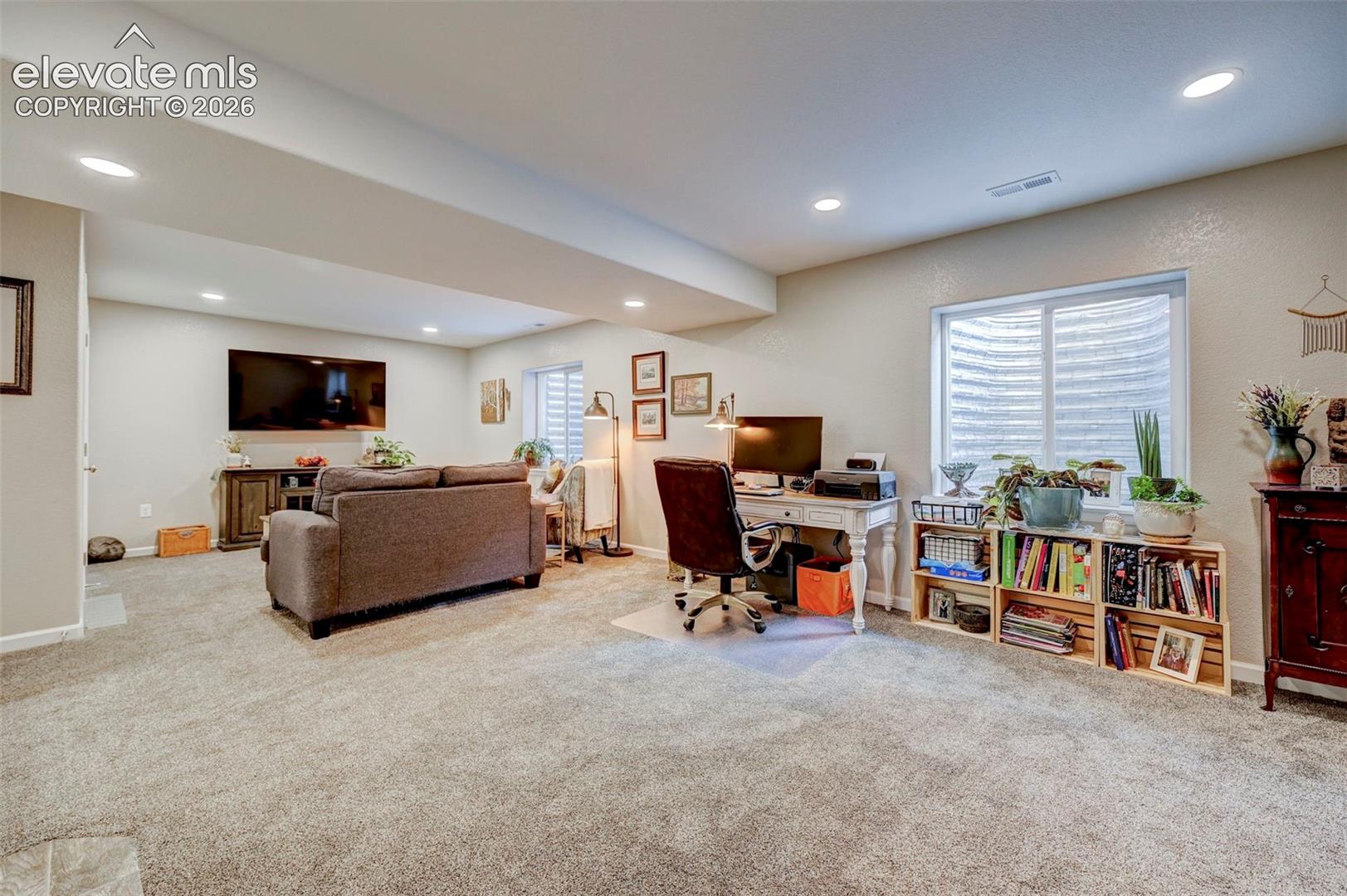 Open-concept interior featuring neutral wall paint, recessed lighting, wall-to-wall carpeting, and multiple egress windows with window wells