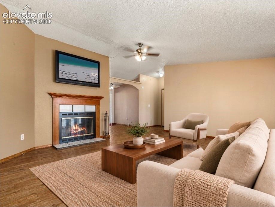 Wood-finish flooring, fireplace with wood mantel, arched doorway, and ceiling-mounted light fixture
