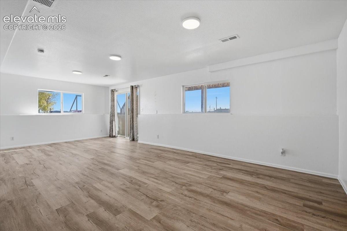 Open-concept interior featuring wood-finish flooring, recessed lighting, dual sliding glass doors, and dual-pane windows