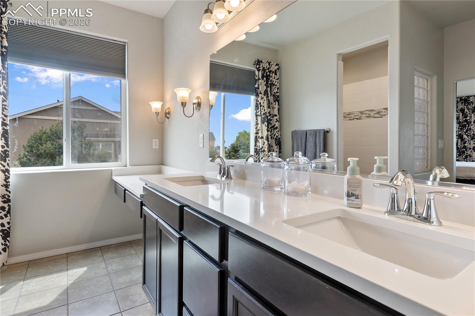 Spacious primary bathroom with dual vanities and connected walk-in closet