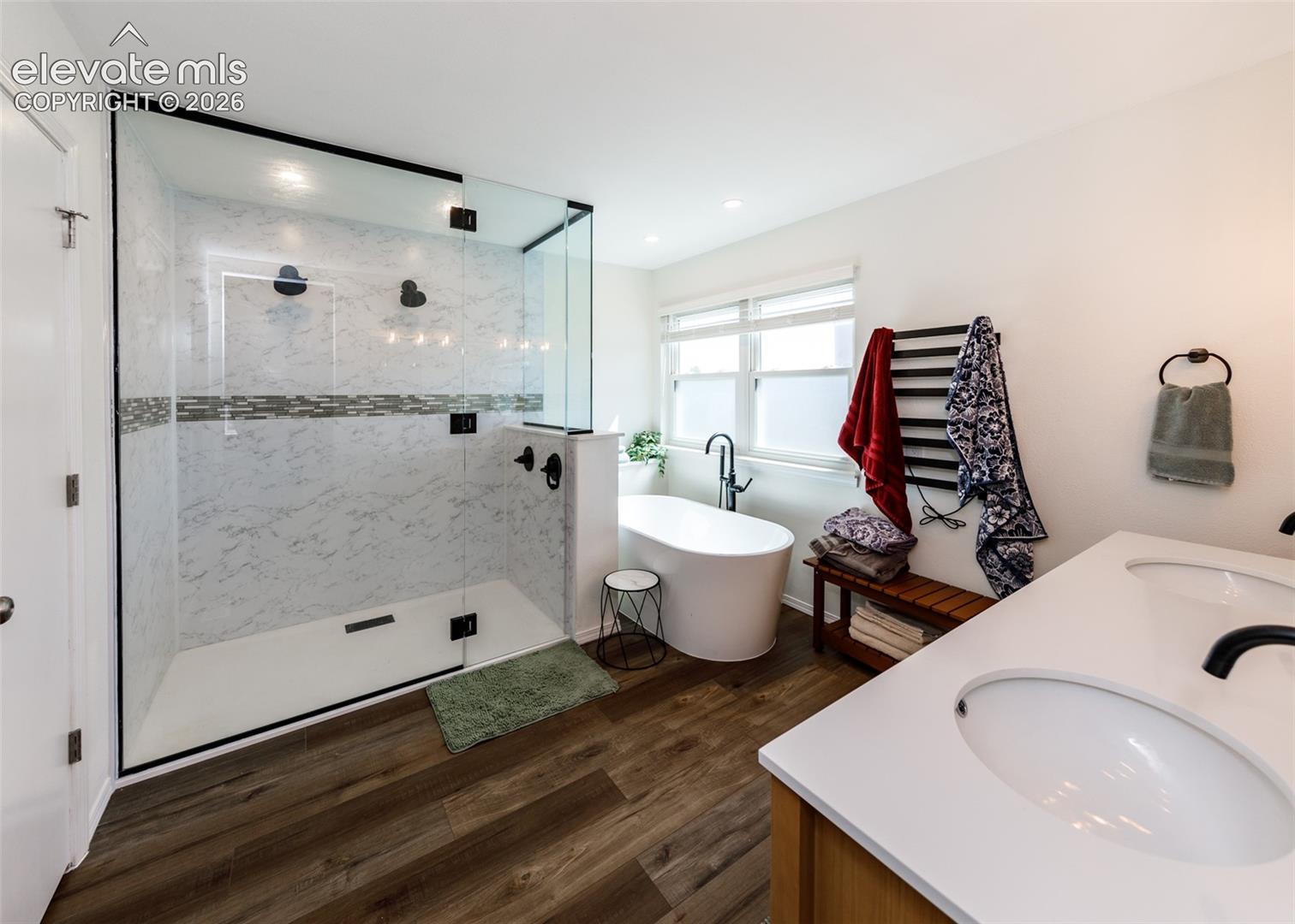 Walk-in shower with clear glass enclosure and marble-look tile