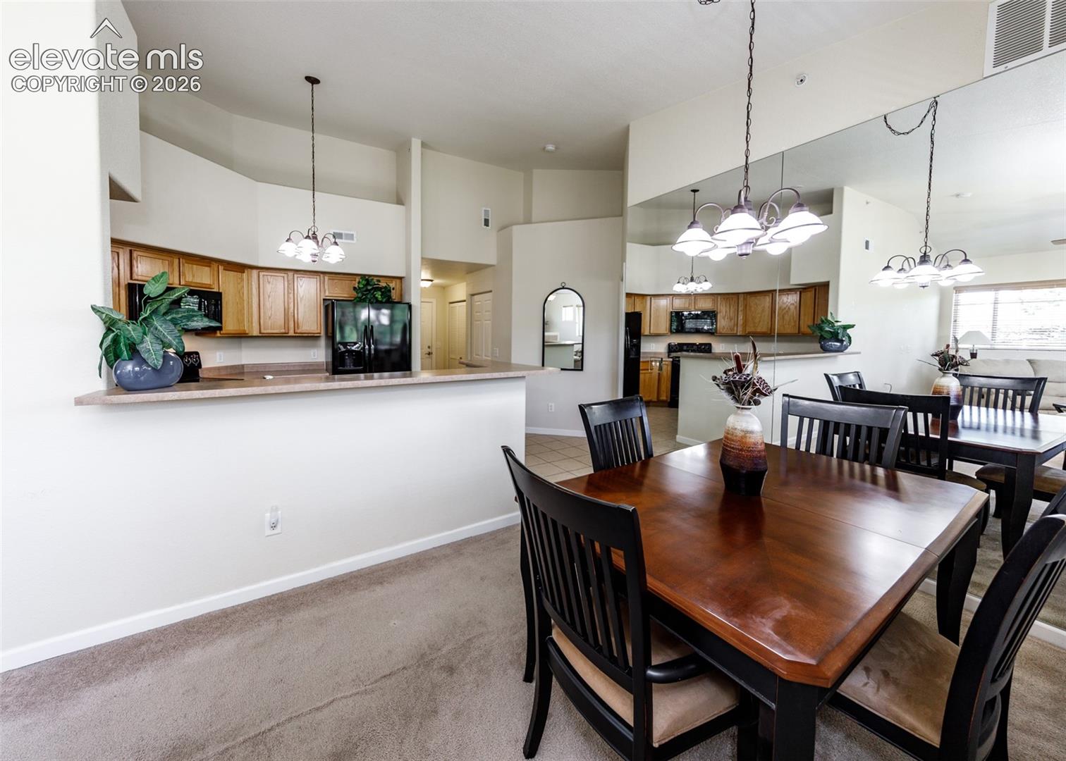 Kitchen featuring wood cabinetry, laminate countertops, and a breakfast bar, complemented by a large wall-mounted mirror and pendant lighting