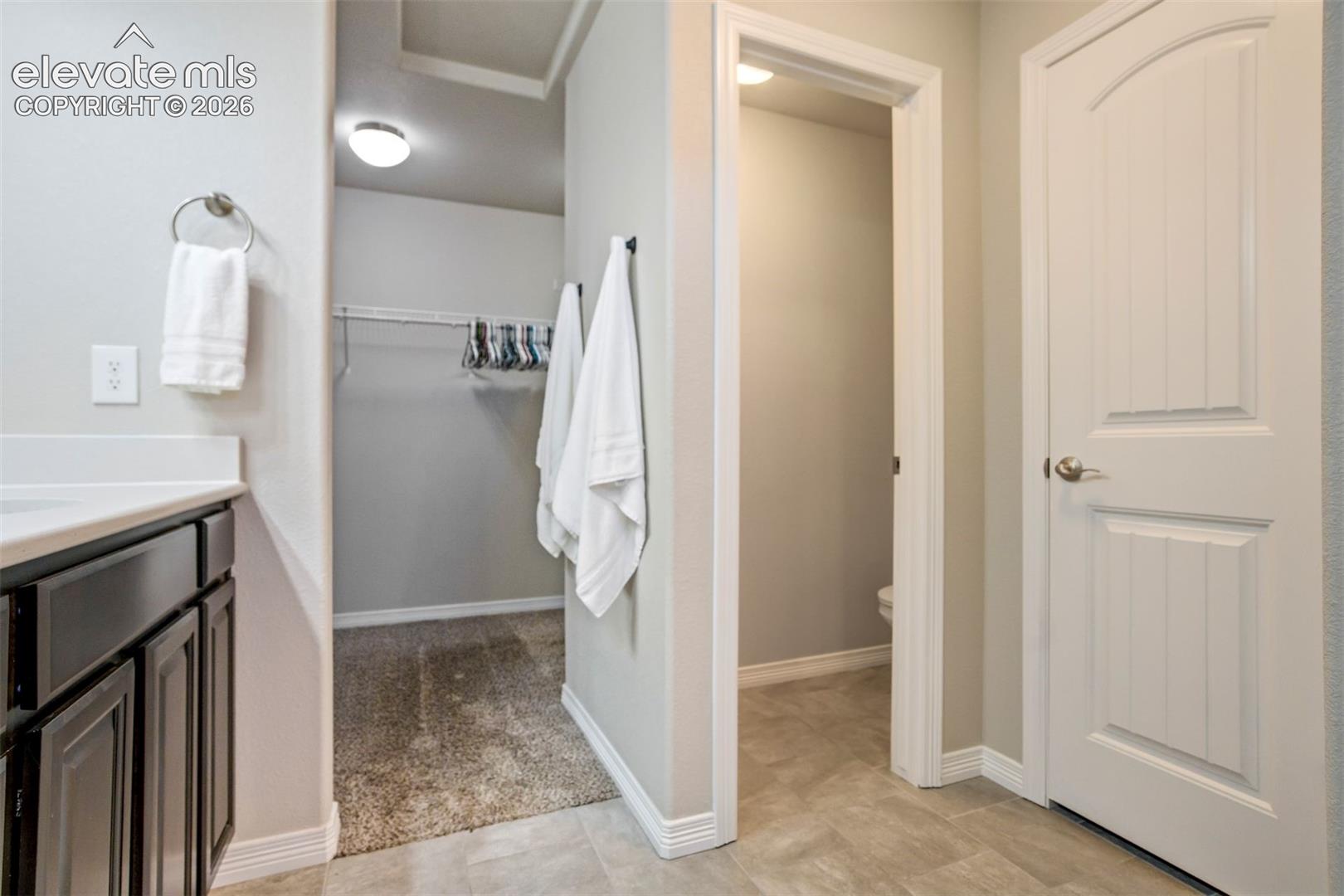 Vanity with white countertop, dark wood-finish cabinetry, and brushed nickel towel ring
