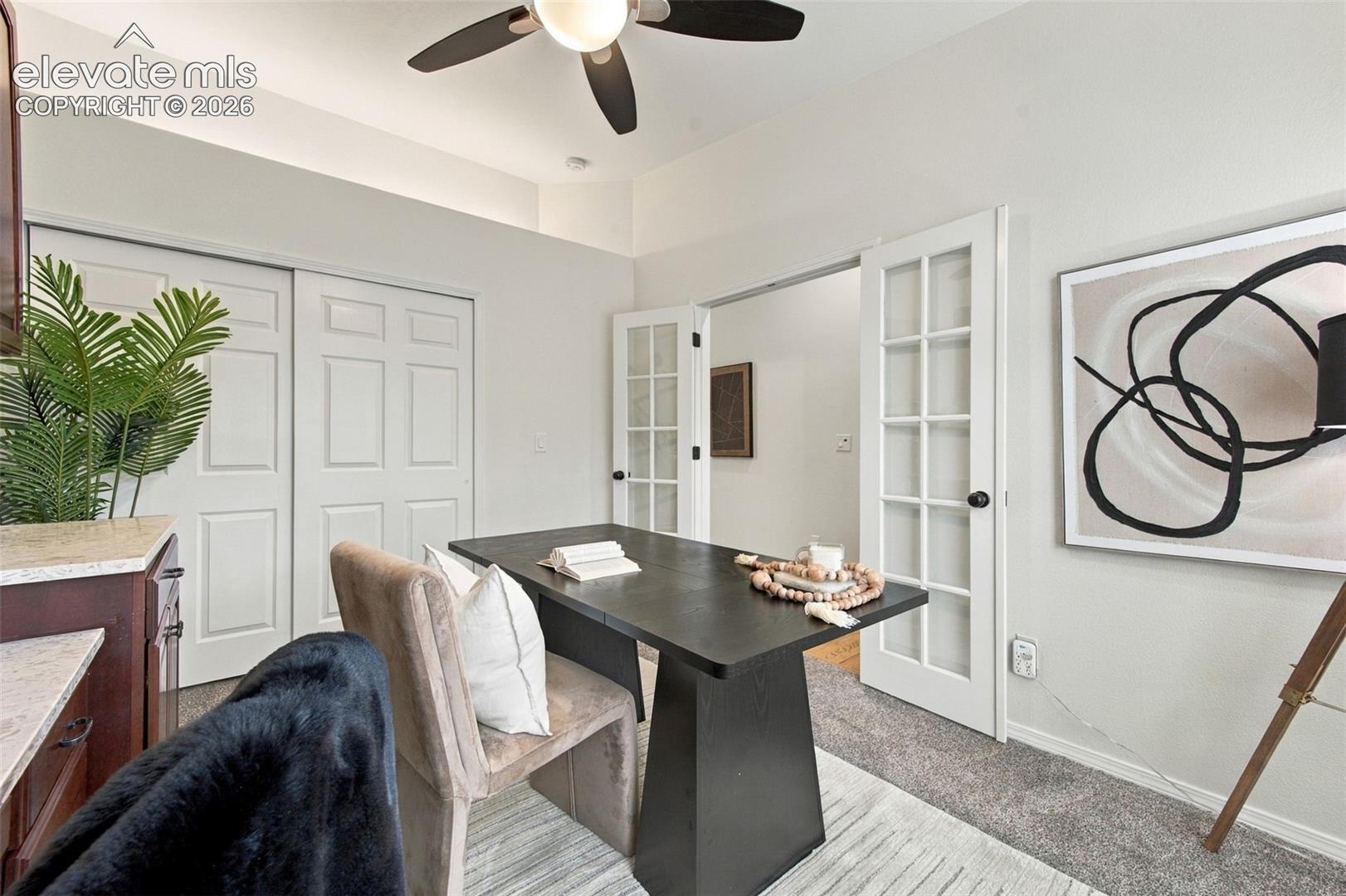 Room featuring high ceilings, a ceiling fan with integrated lighting, sliding closet doors, and glass-paneled French doors