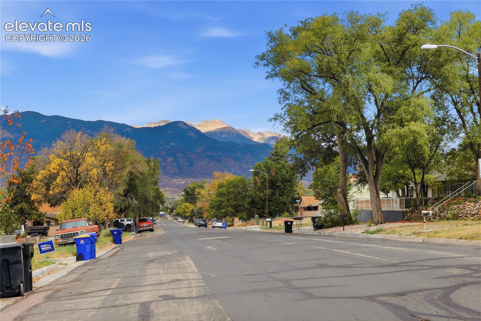 Streetscape featuring mature trees and prominent mountain backdrop