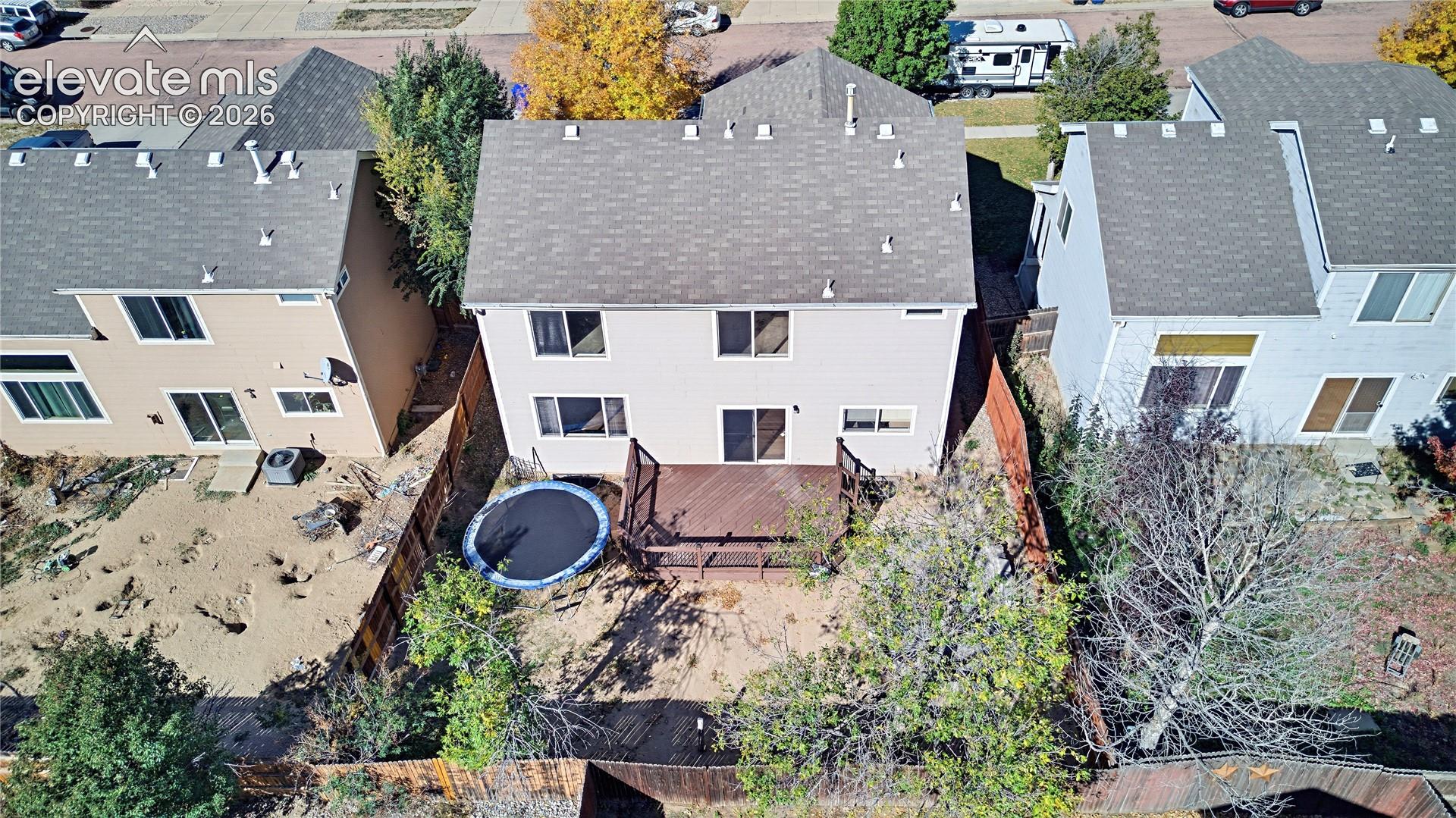 Rear exterior featuring an elevated wood deck, private wood fencing, and multiple windows