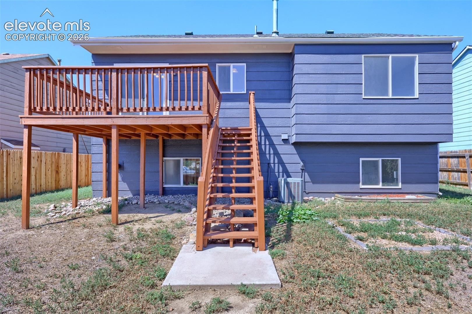 Elevated wood deck with baluster railing, wood staircase, and horizontal siding