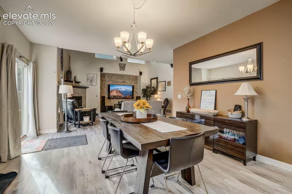 Dining area featuring wood-finish flooring, a contemporary chandelier, and a wood dining table