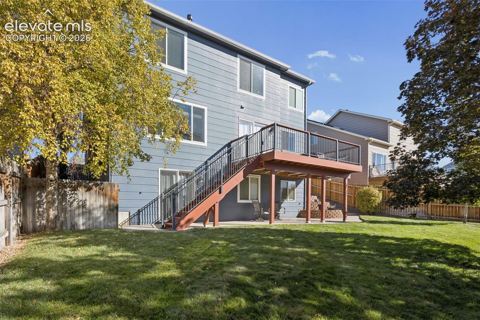 Rear exterior featuring newer deck with metal railings, expanded concrete patio off basement walk-out and a nice fenced backyard