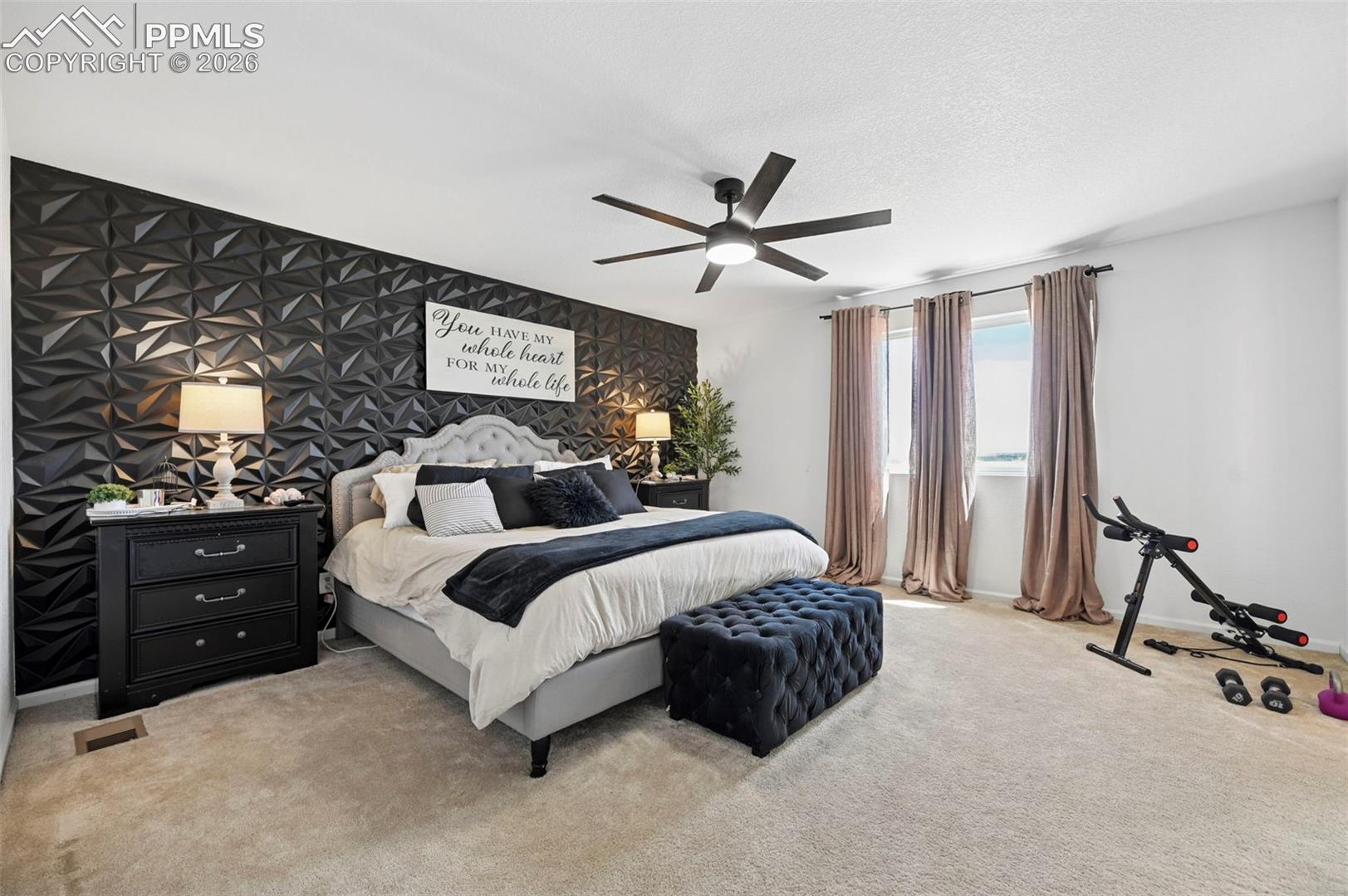 Textured accent wall, neutral carpet flooring, and a contemporary ceiling fan with integrated lighting