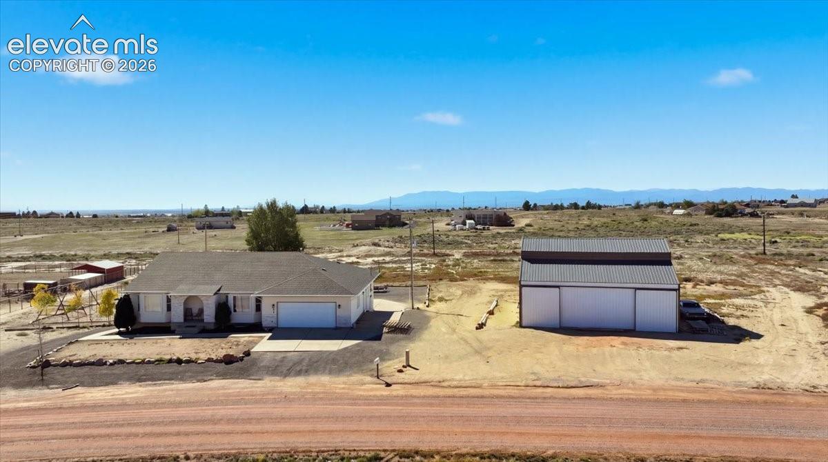 Single-level residence featuring an attached garage and a detached multi-bay workshop, set on a sprawling acreage lot with mountain scenery