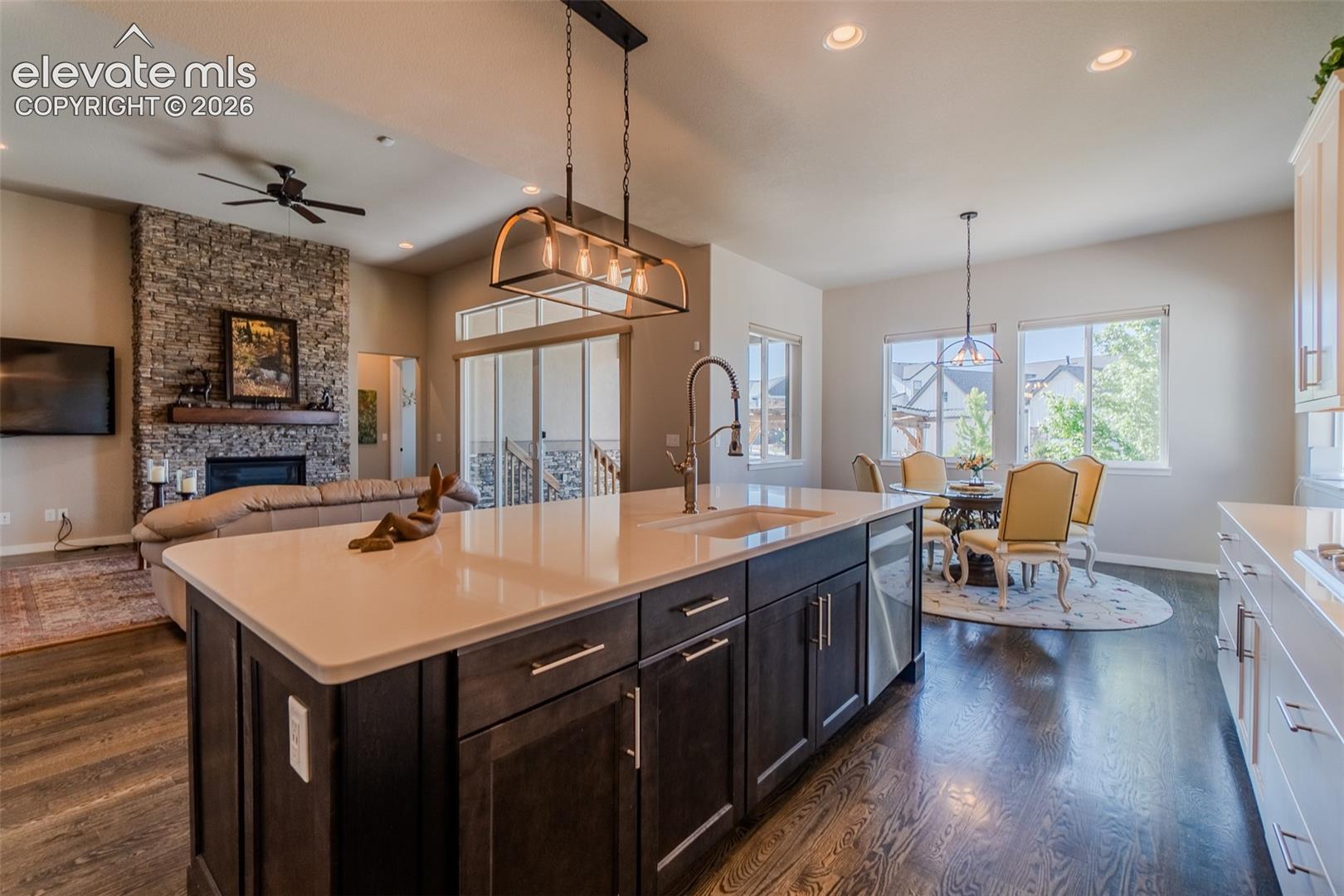 Kitchen island featuring a white countertop, undermount sink, and dark wood cabinetry